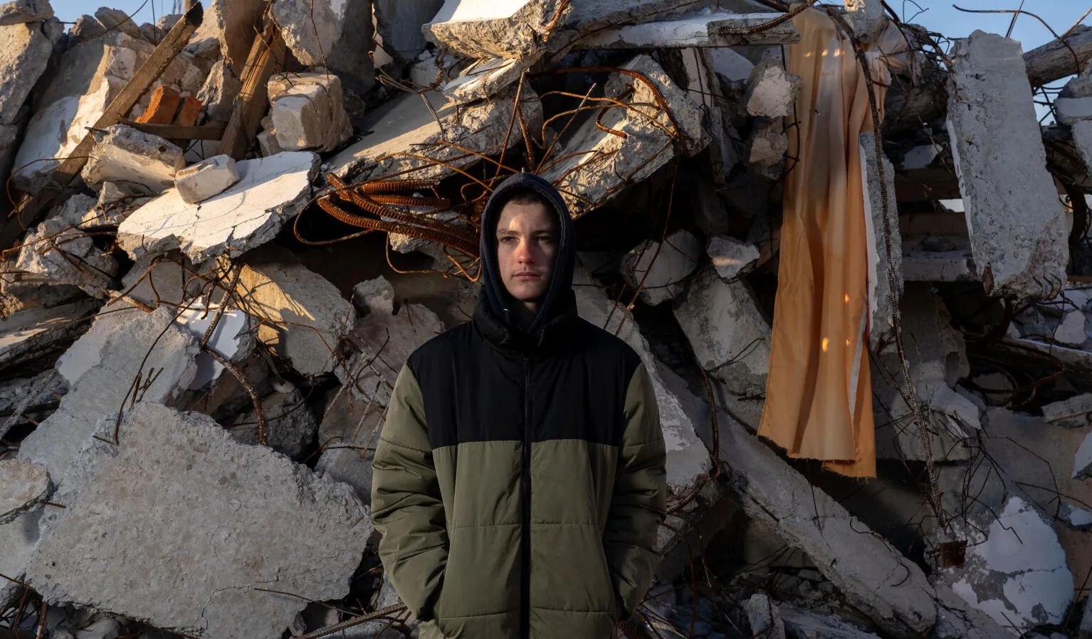 En Ukraine, un garçon se tient devant des décombres.