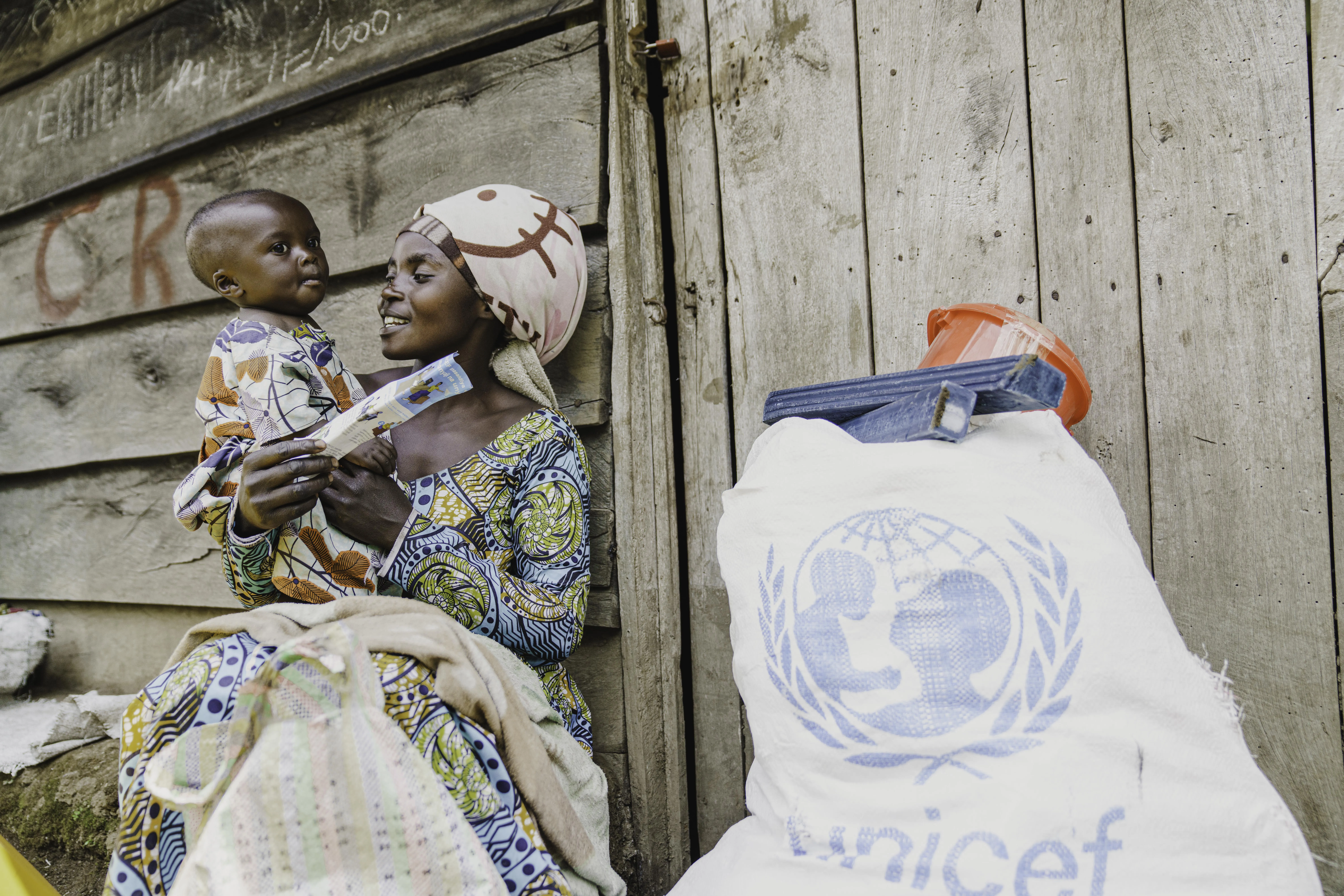 Judith, a mother of three, sits in front of her shelter with her child after receiving essential household items at the distribution site in Rugari, Rutshuru territory, North Kivu province, DR Congo, on 27 February 2025.