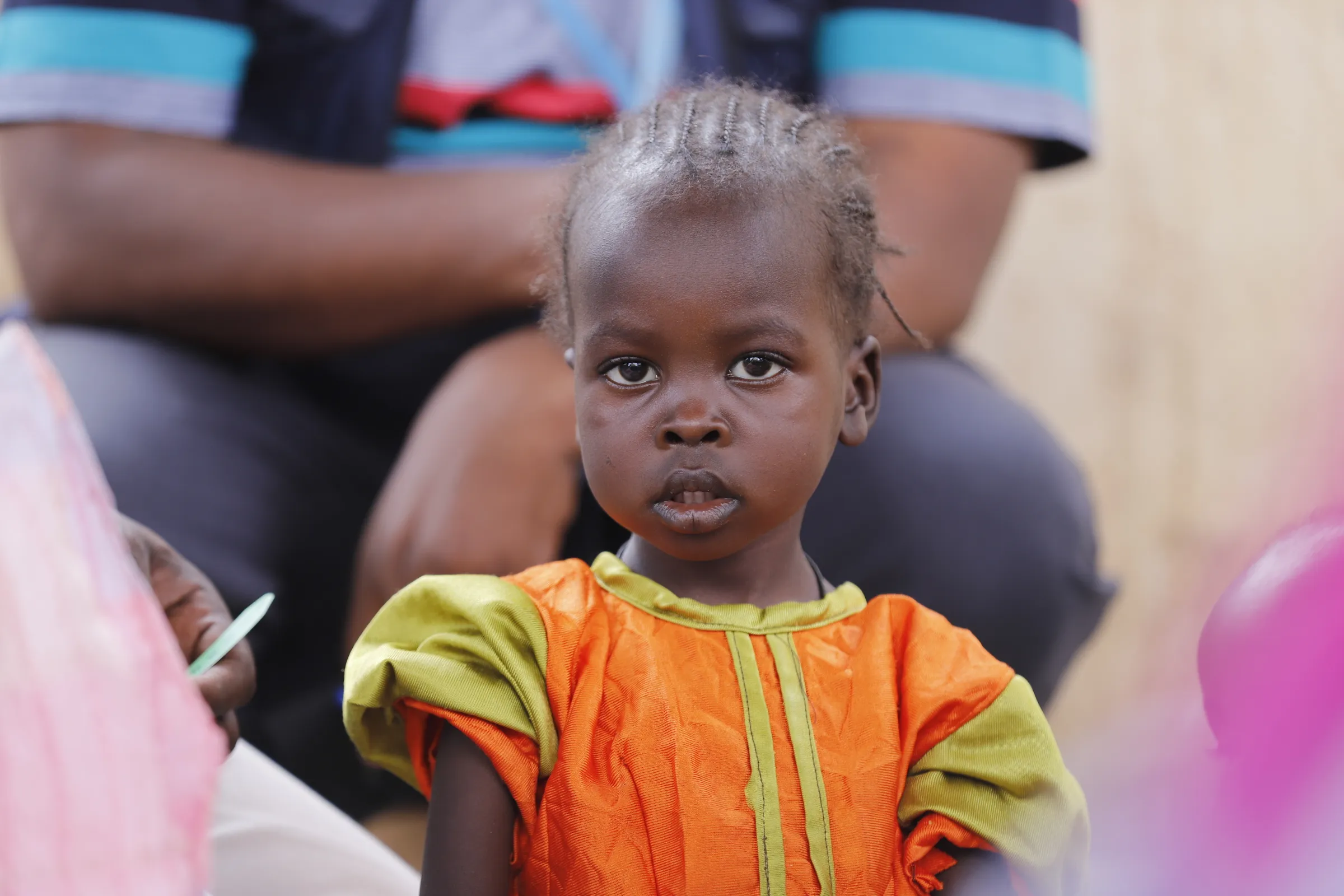 A child looks on as health workers screen children for malnutrition at a UNICEF-supported Primary Health Clinic in Tawila, North Darfur, Sudan