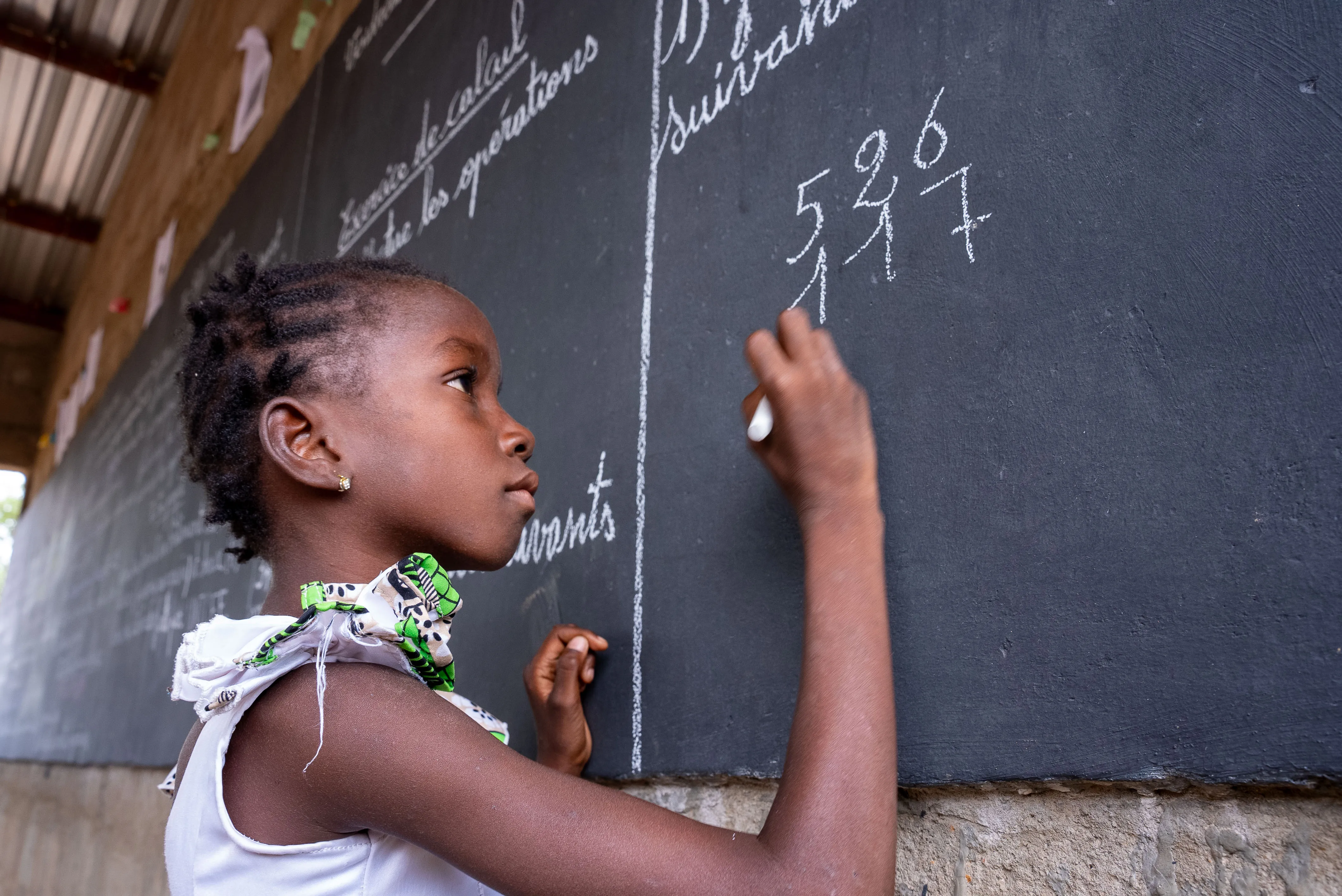 Une fille écrit sur un tableau dans un espace d’apprentissage temporaire (TLS) à Fada N'Gourma, dans la région de l’Est, au Burkina Faso.