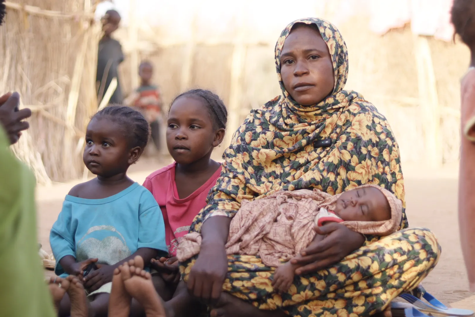 Amani carries her newborn baby next to her makeshift shelter in Tawila where she fled with her family after intensified fighting back home in Al Fasher, North Darfur.