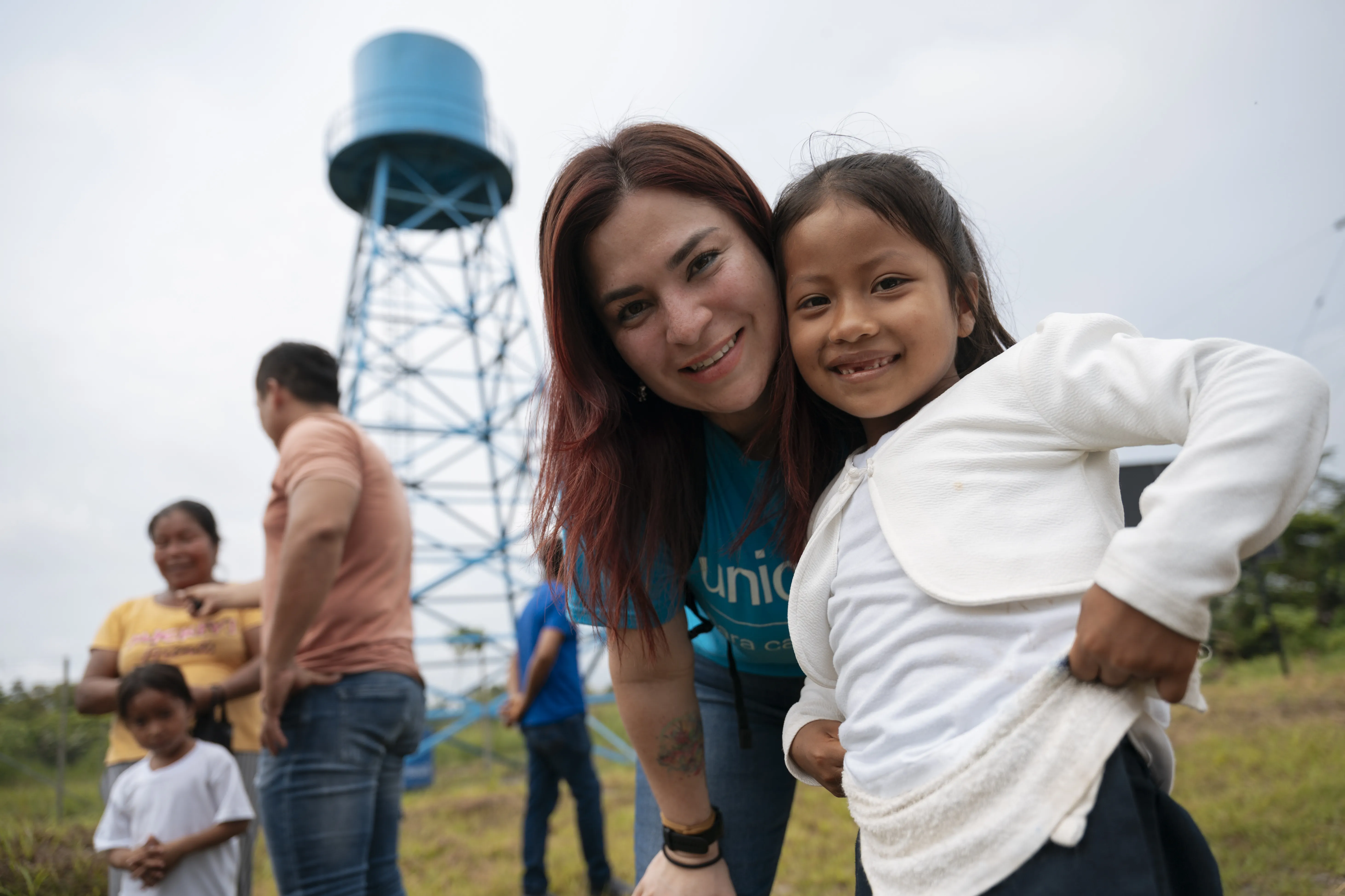 UNICEF worker and girl smiling together near a water tower in Sucumbíos, Ecuador.