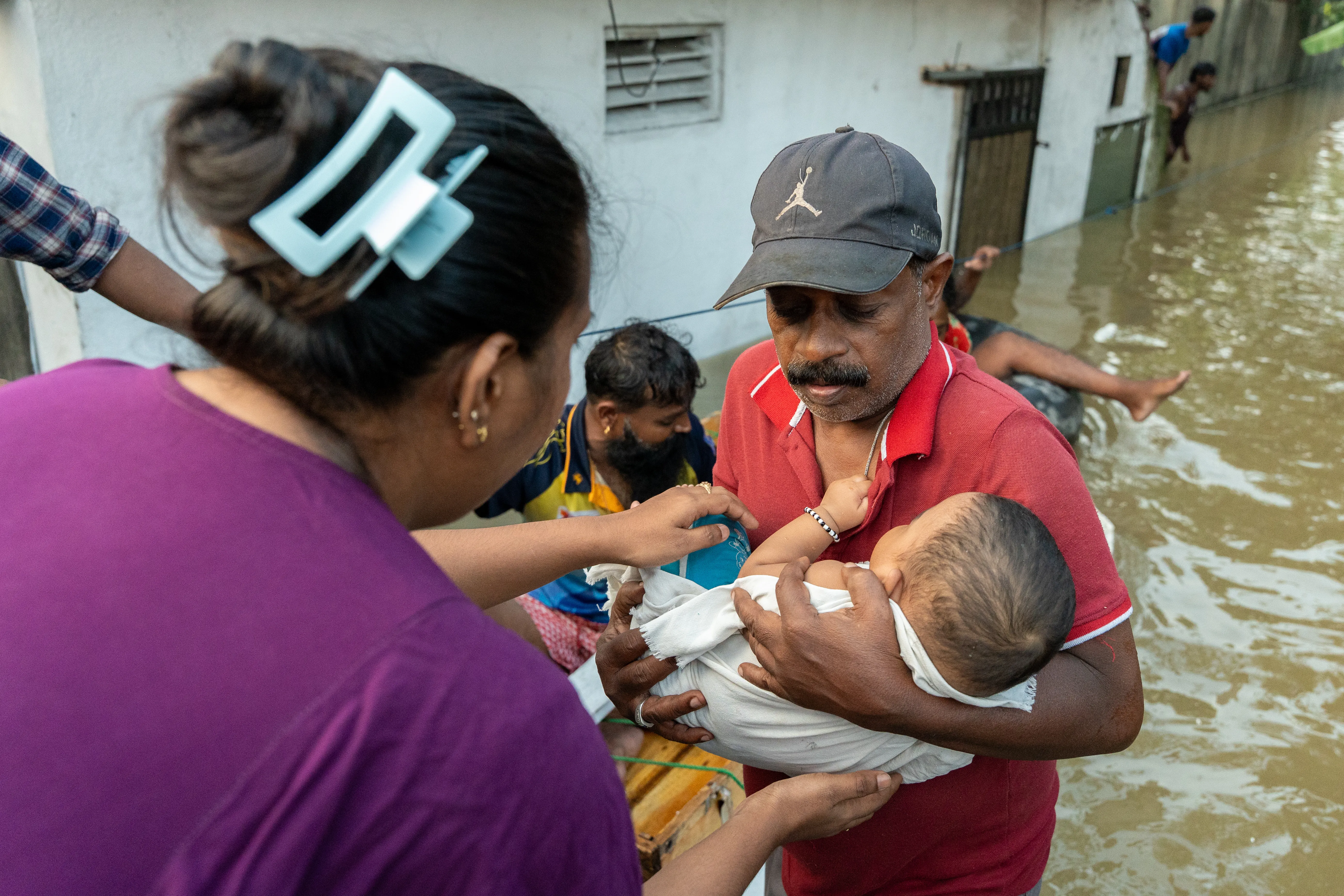 Des secouristes sri-lankais aident à transporter une famille bloquée avec un bébé à bord d'un bateau de sauvetage
