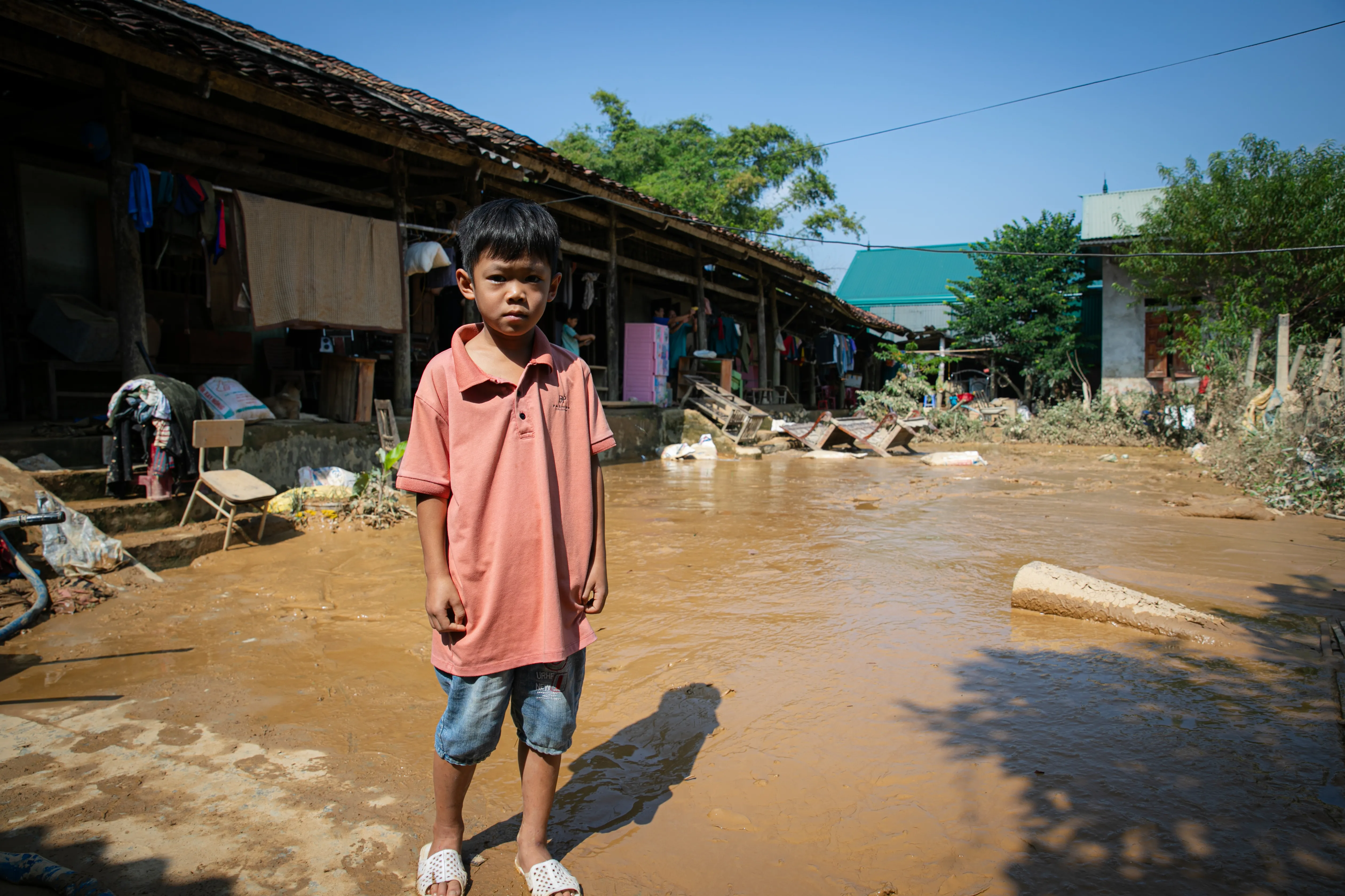 Un enfant se tient debout dans les eaux de l'inondation près de sa maison au Vietnam.