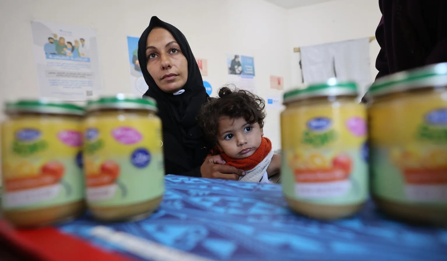 A mother holds a child while waiting to receive ready-to-use-complimentary-food.