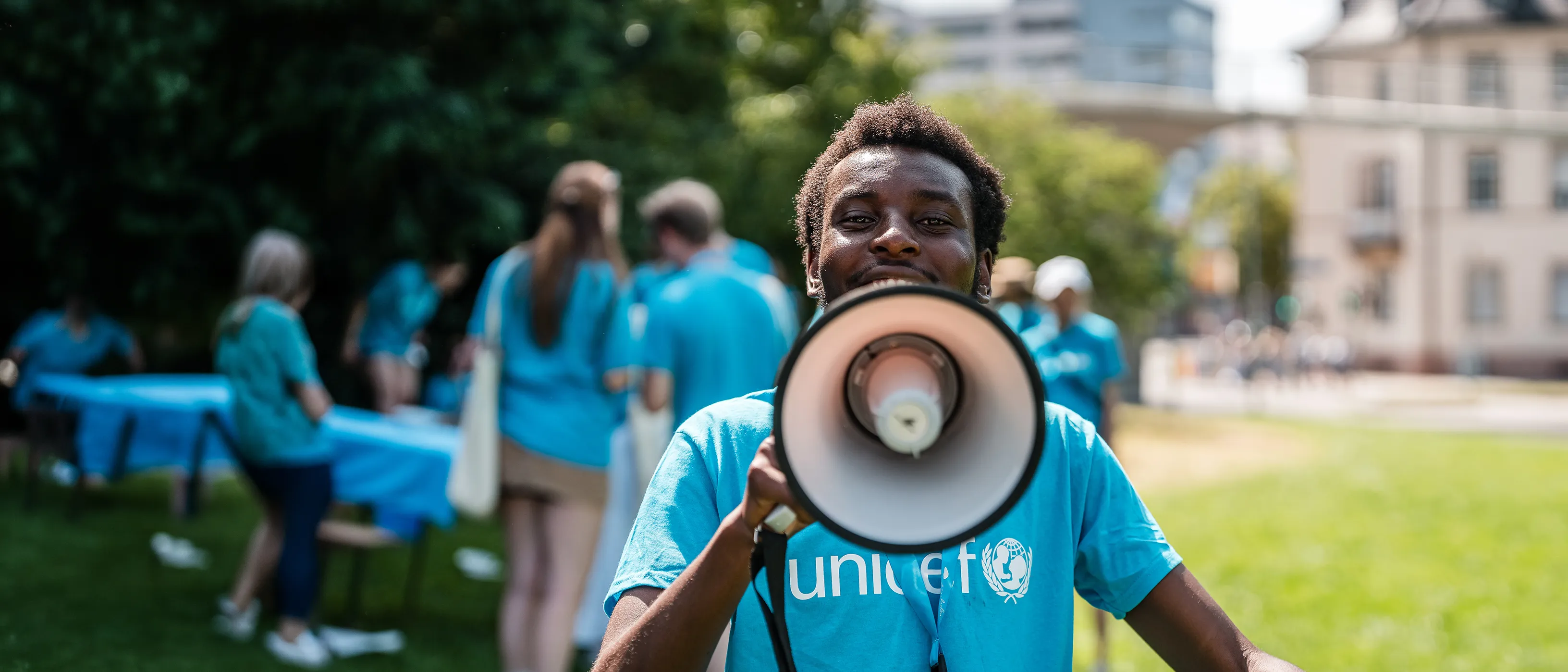 Youth in a blue UNICEF t-shirt speaking into a megaphone.