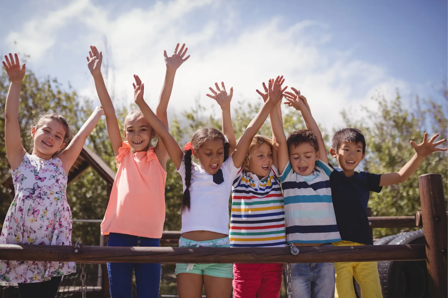 Children smiling with their hands raised in the air.