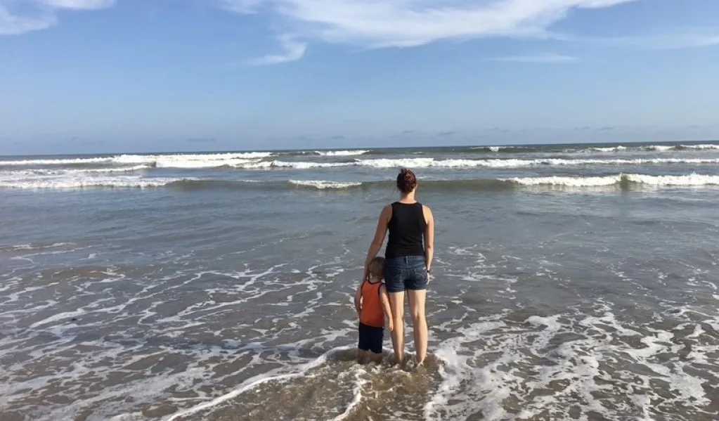 Bethany stands on a beach in Ghana with her son.