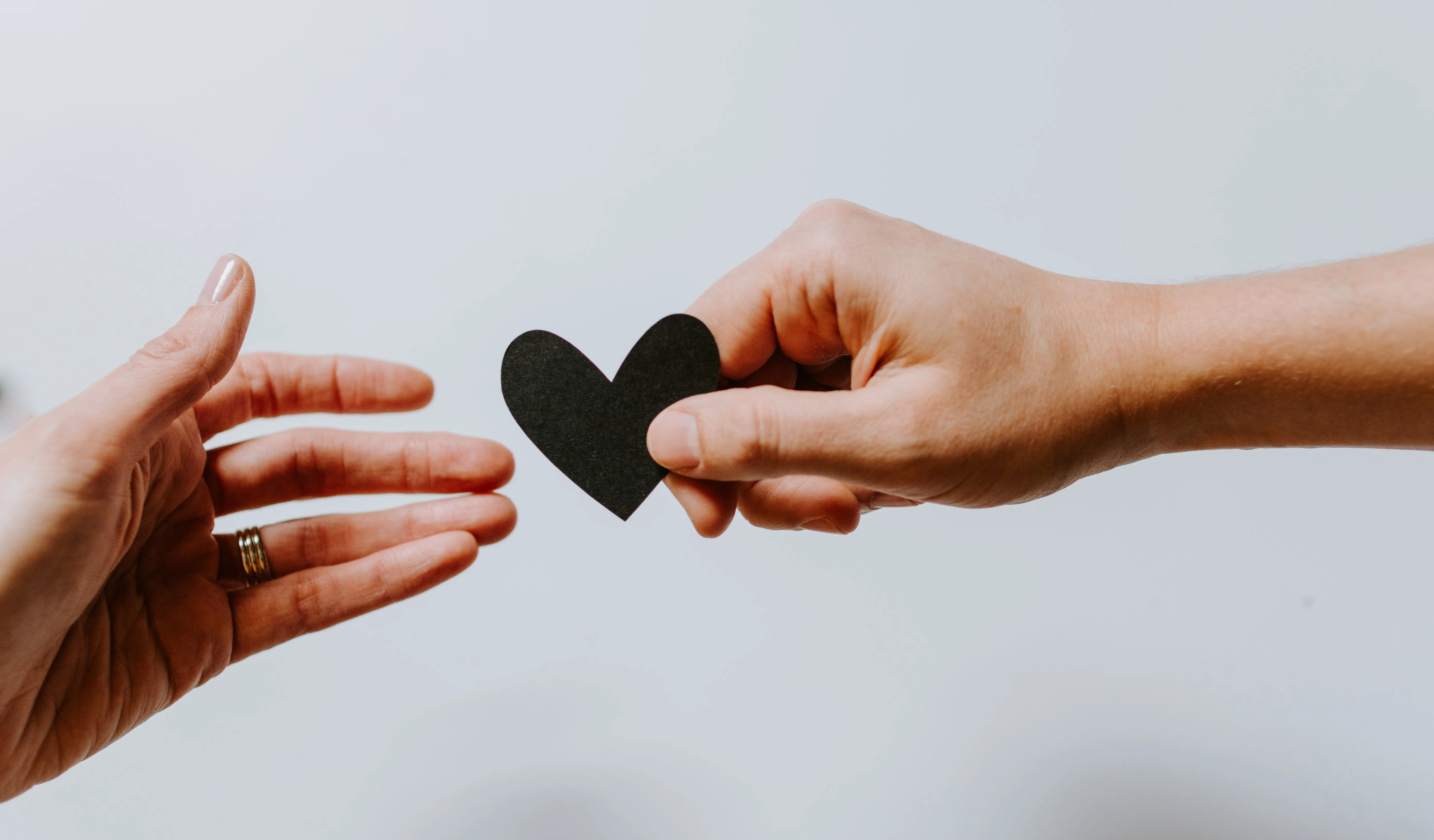 A person passes a small heart cut out to another person