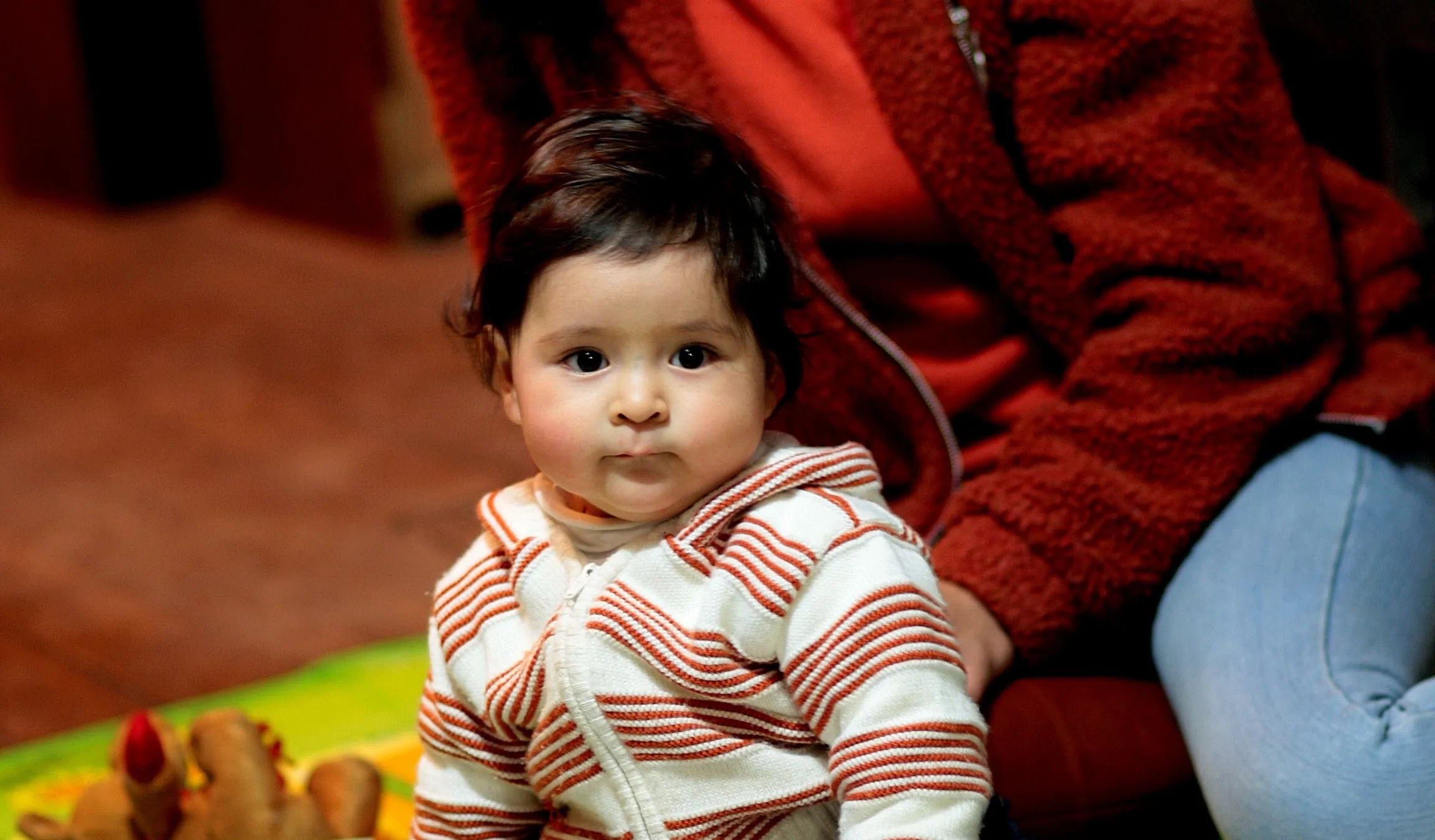 Une mère et son enfant assis par terre regardent un livre d’images.