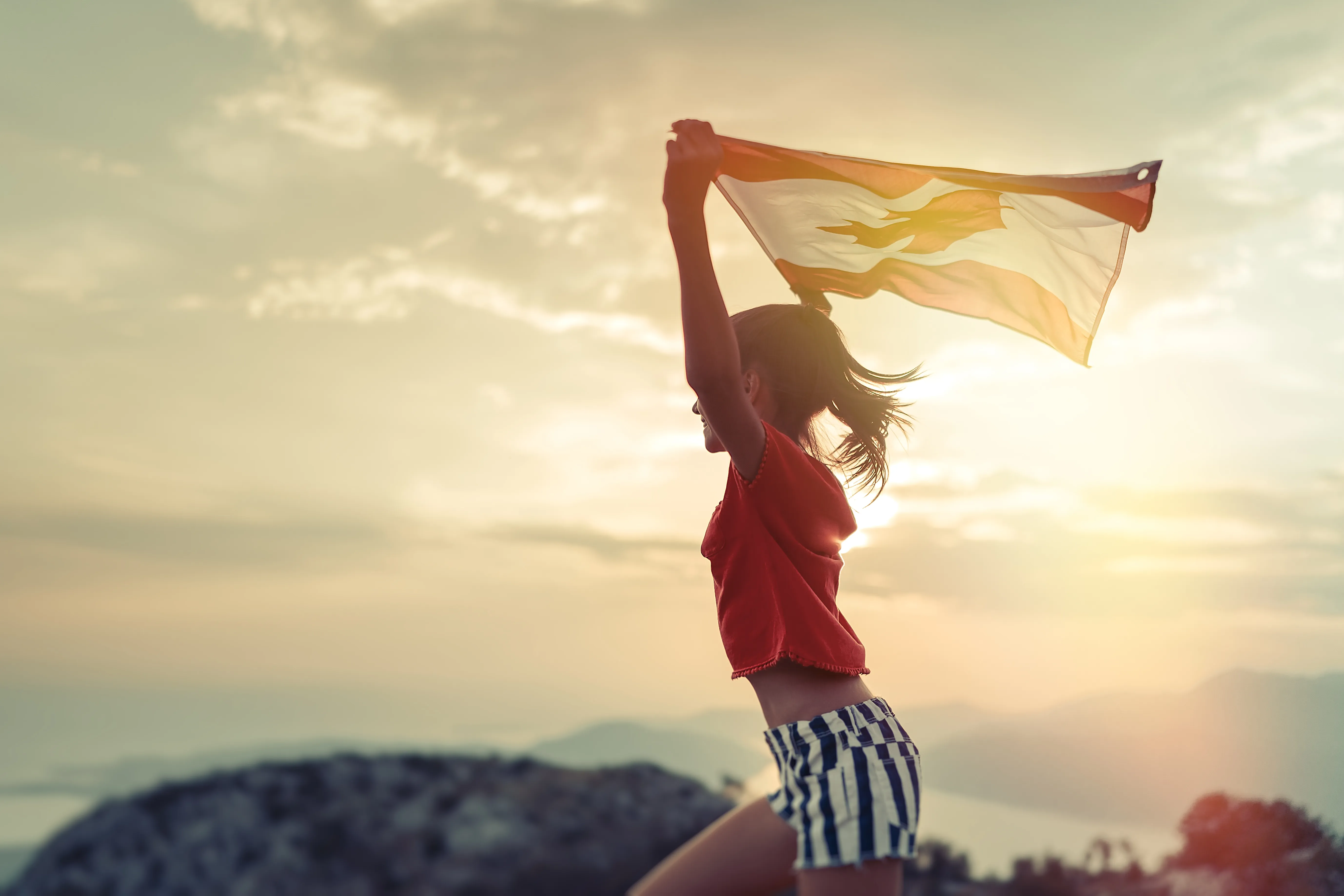 Young person running while holding Canadian flag