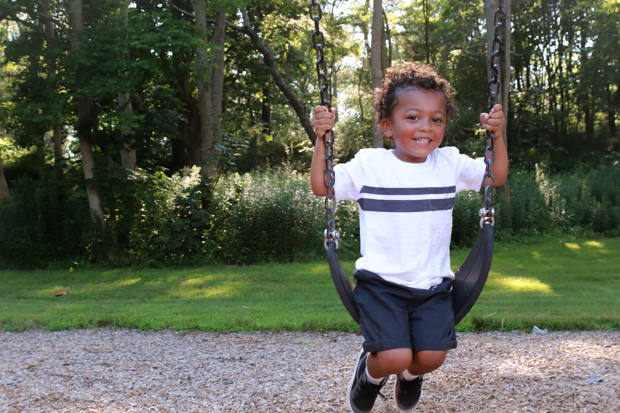 Young boy smiling on a swing set