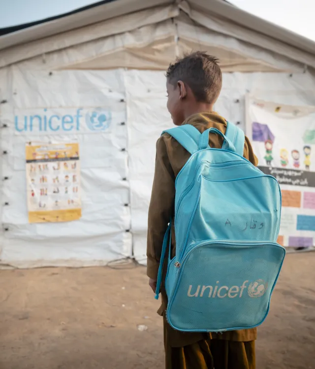 Boy with a UNICEF backpack facing a UNICEF learning centre tent in Sindh, Pakistan.