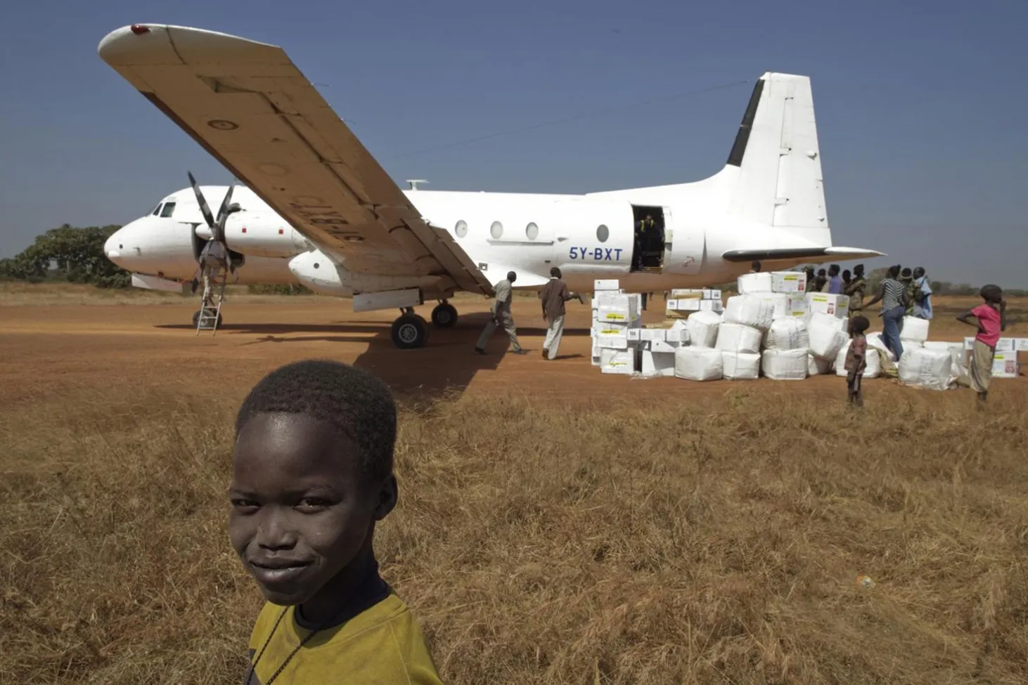 Children in northern South Sudan watch workers unload a shipment of polio vaccines
