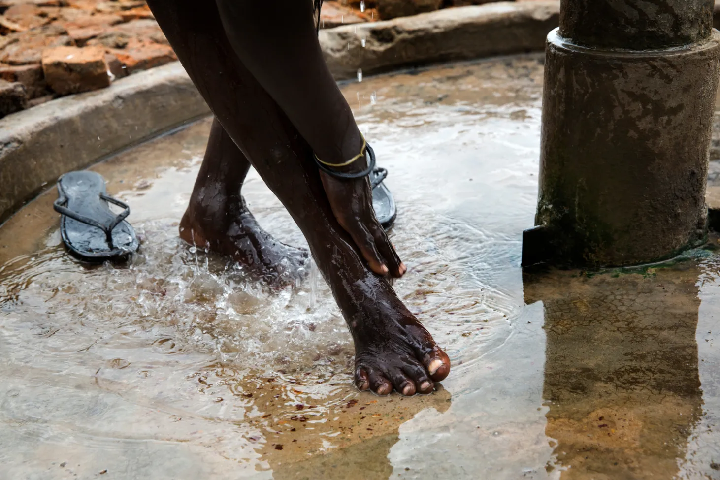 une femme se lave à une pompe grâce à l’eau de l’usine de traitement