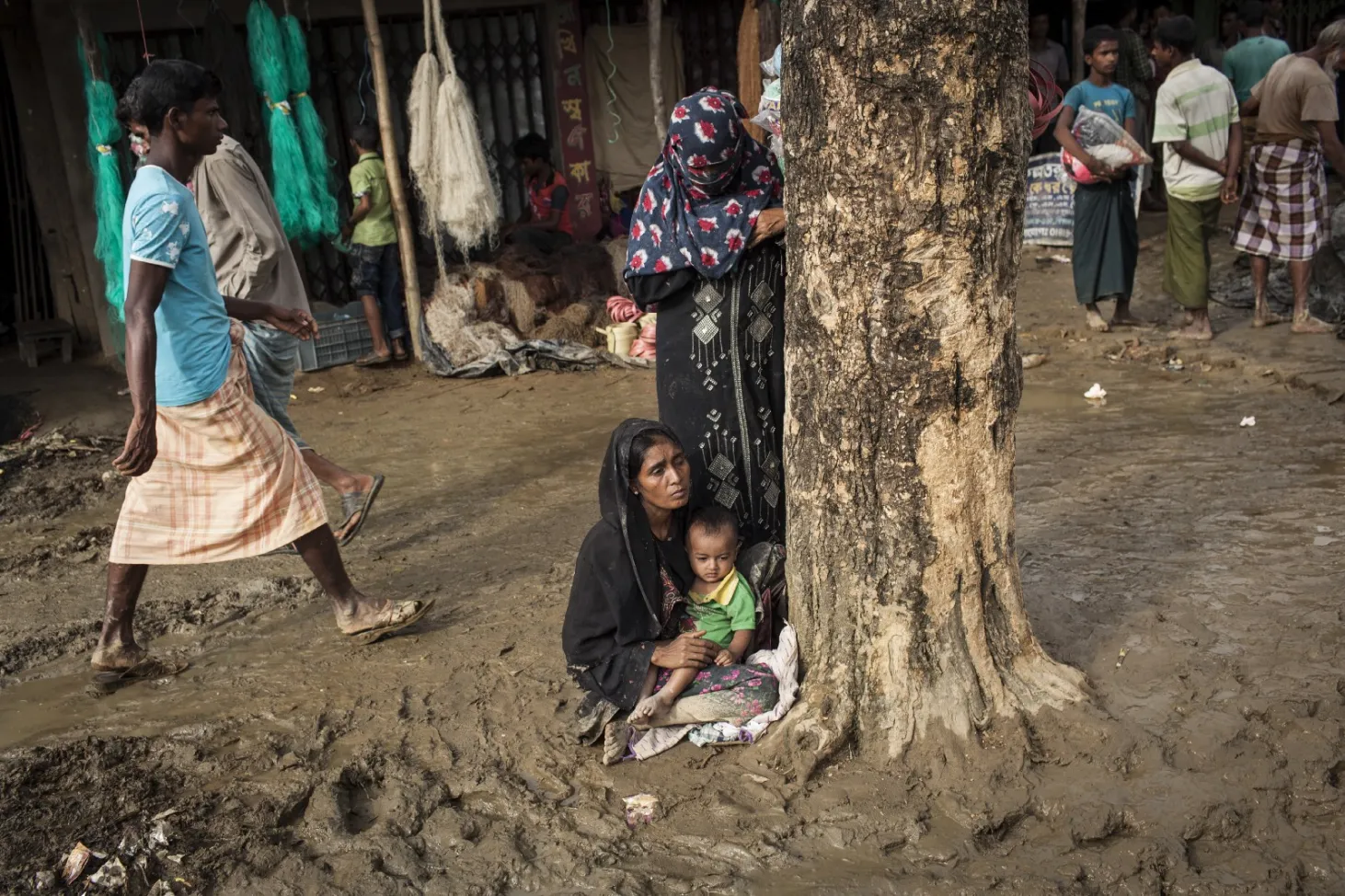 Une femme tenant un enfant se repose dans la boue