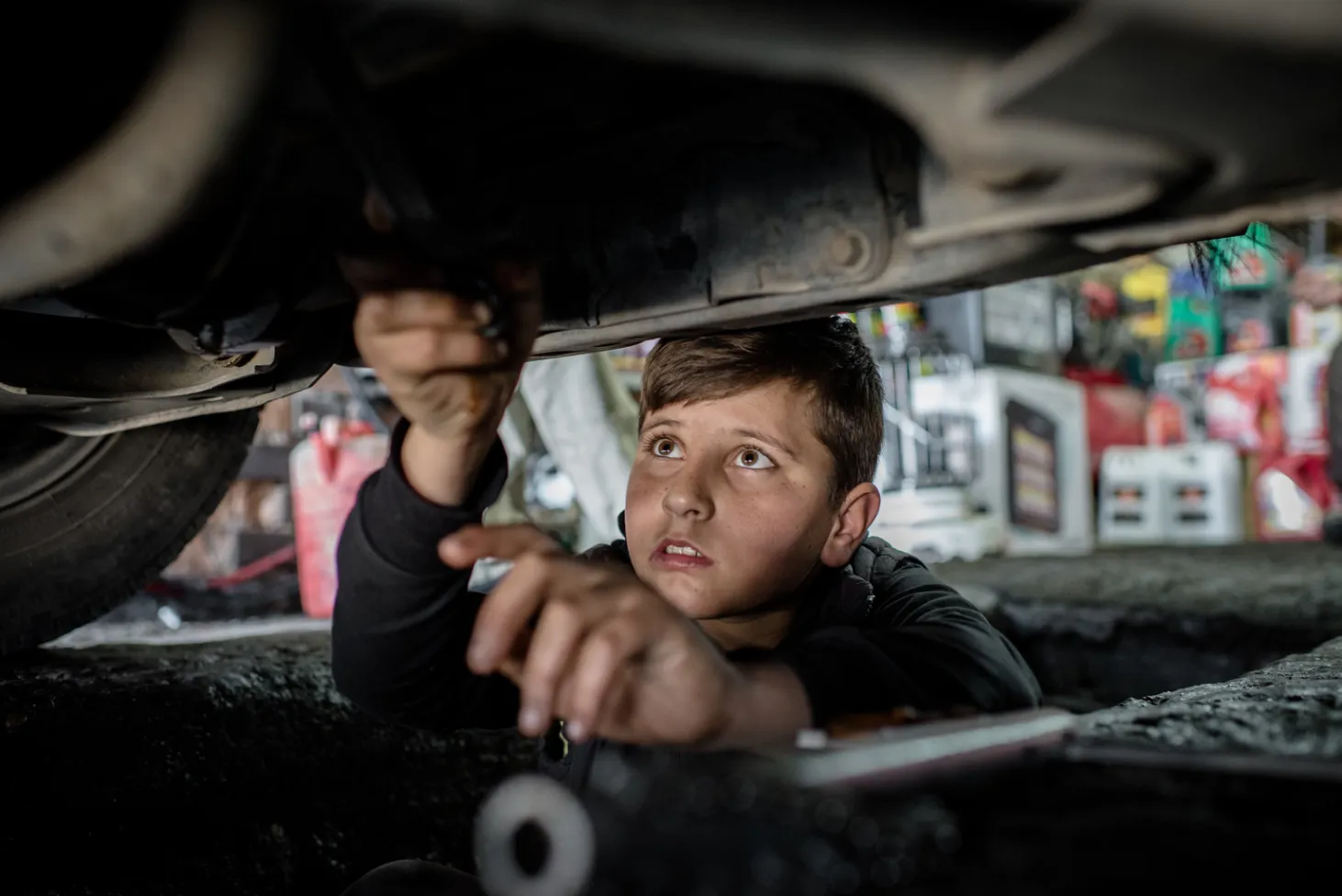 Mohammed, 14 ans, réfugié syrien de Kobani, travaille sous une voiture