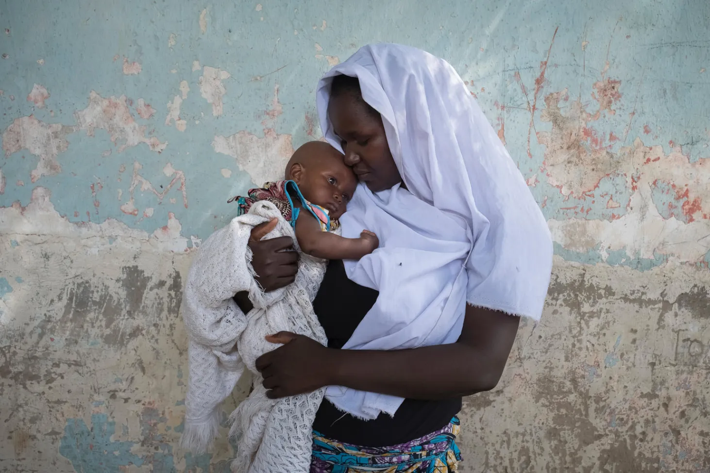 Esther tient son enfant dans ses bras.