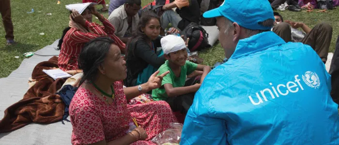 Nepal: UNICEF worker attends to an injured woman and her son just after the first earthquake hit in 2015Au Népal, un intervenant de l’UNICEF vient en aide à une femme blessée et à son fils après le premier séisme qui a frappé le pays en 2015.