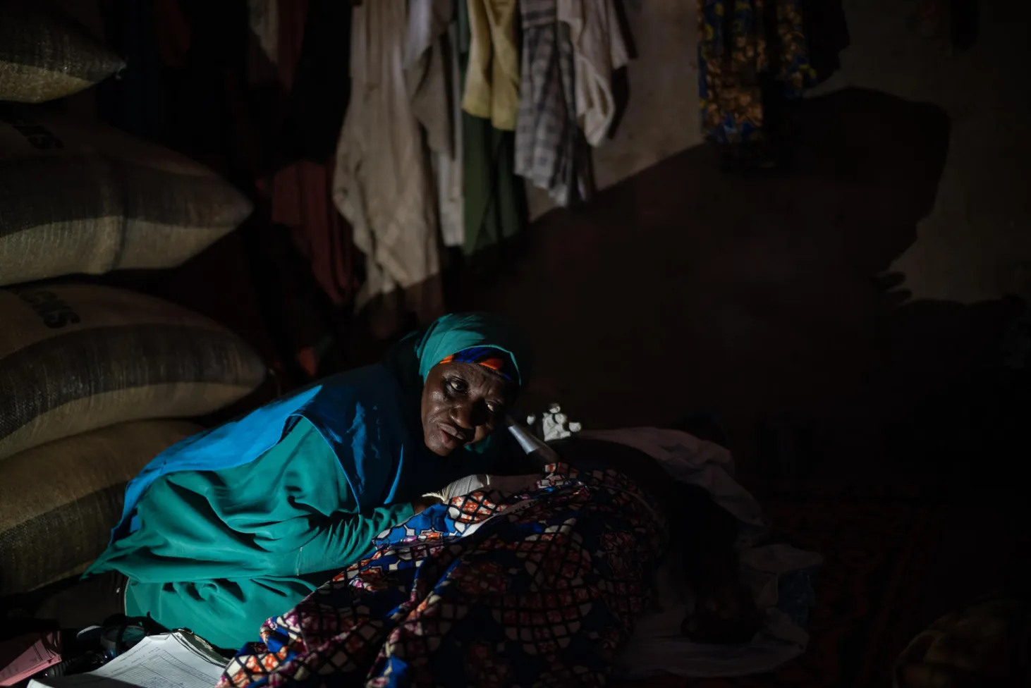 Une femme portant un voile vert est assise dans une clinique de santé maternelle et infantile soutenue par l’UNICEF. 
