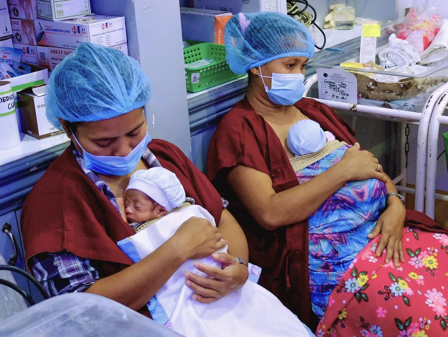 Mothers sitting with their premature newborns in intensive care unit.