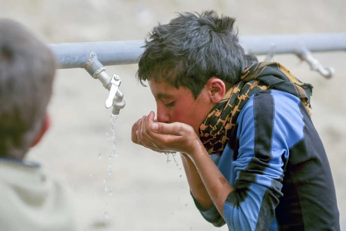 Mohammad, 13, drinking water in Karama refugee camp