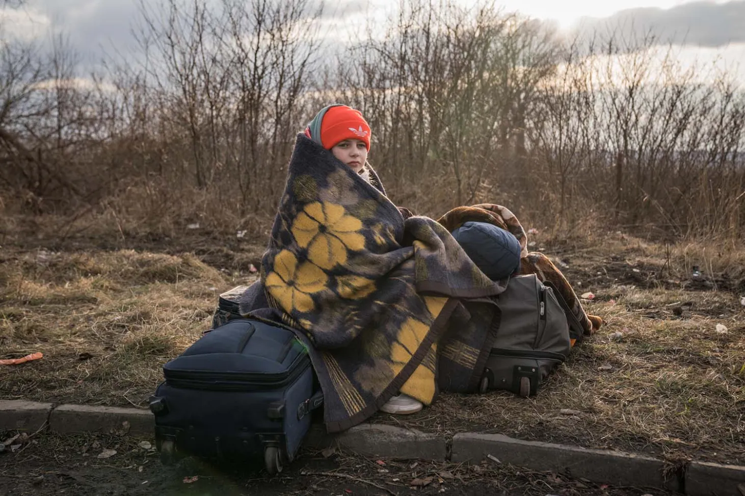 Girl sits by the road fleeing Ukraine