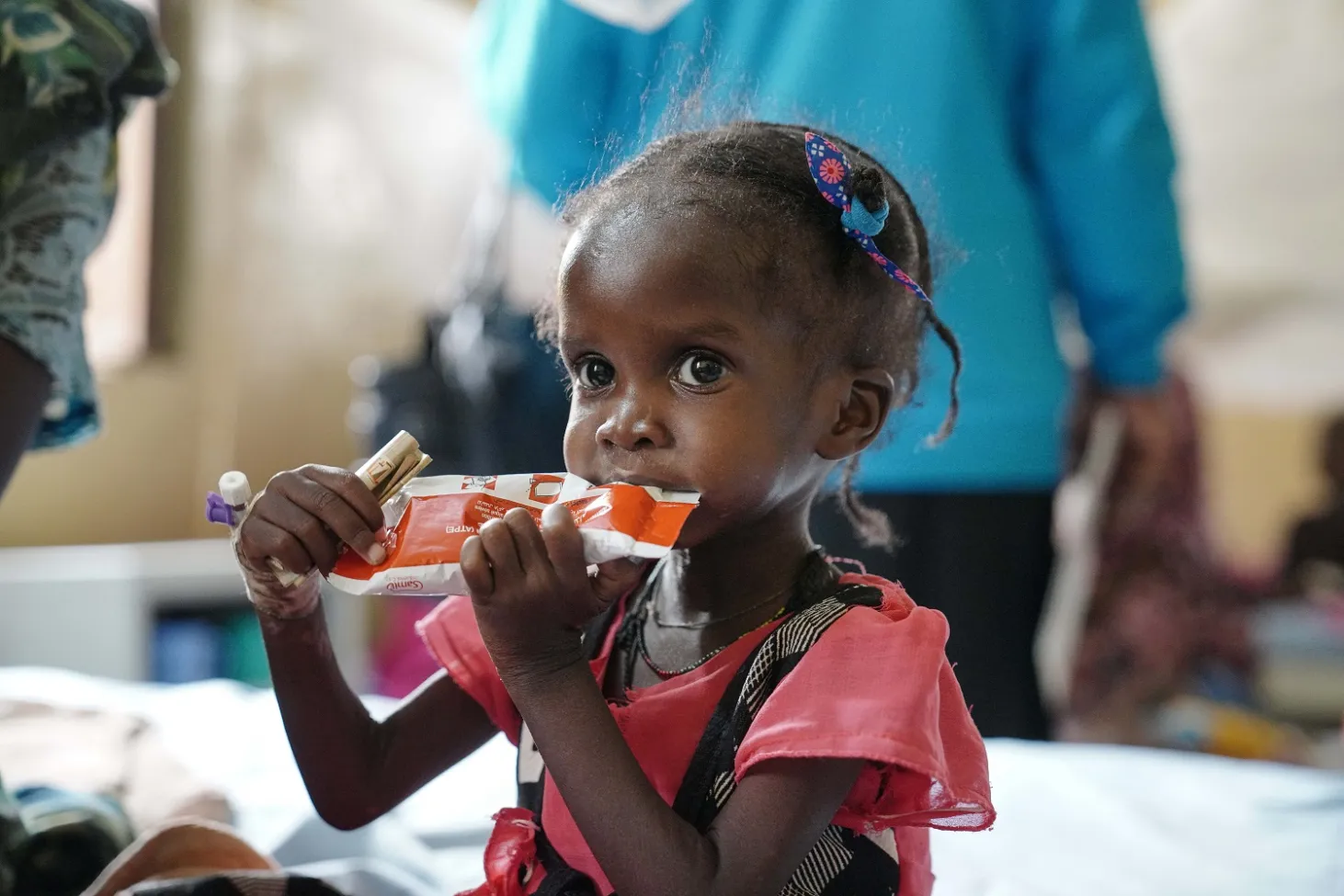 In Sudan, 2-year-old Israa eats from a packet of therapeutic food called Plumpy’Nut. 