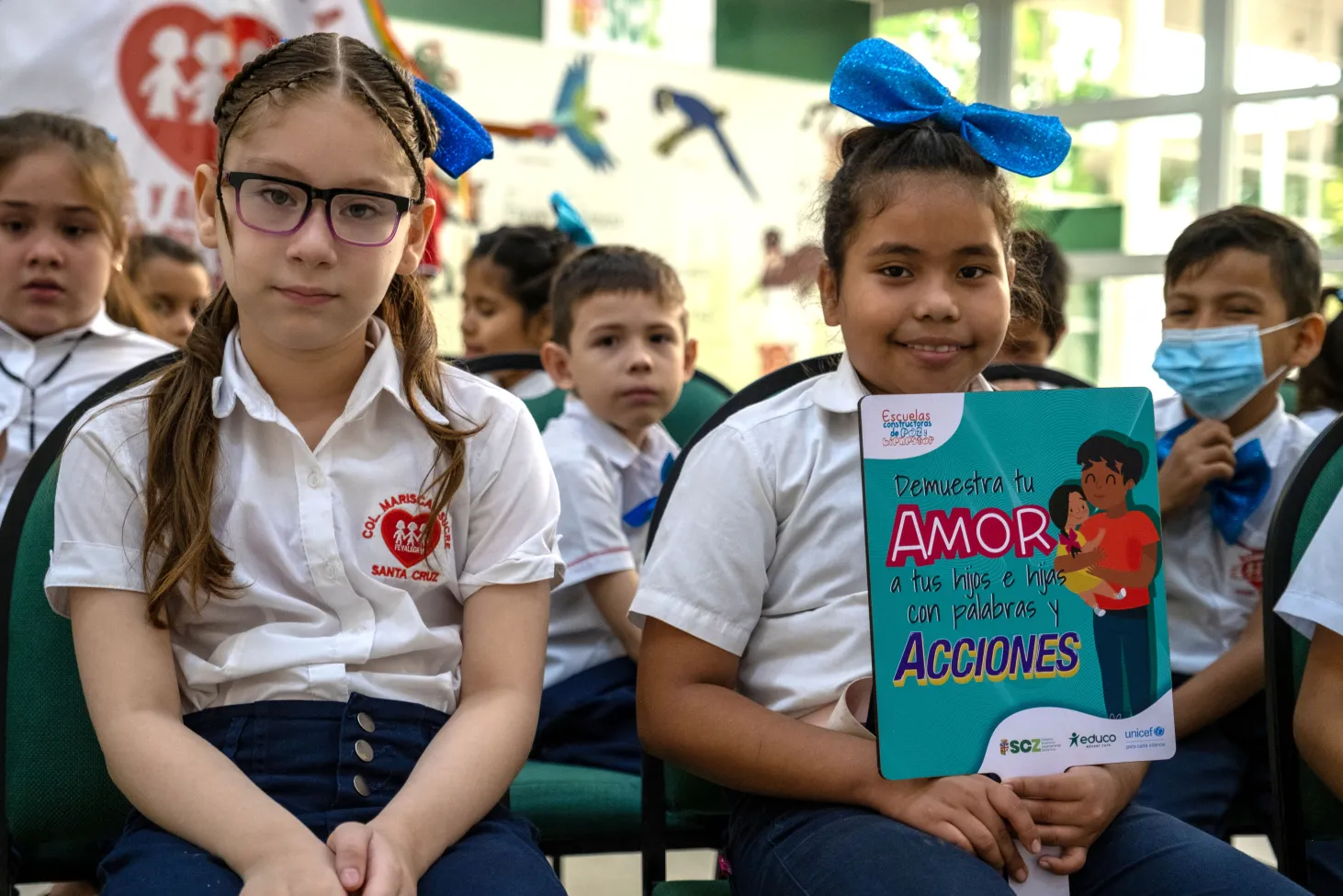 Deux jeunes filles en uniforme assises dans un auditorium lors d’une cérémonie sur la prévention de la violence à l’encontre des enfants dans une école à Santa Cruz, en Bolivie. Les deux enfants regardent la caméra.