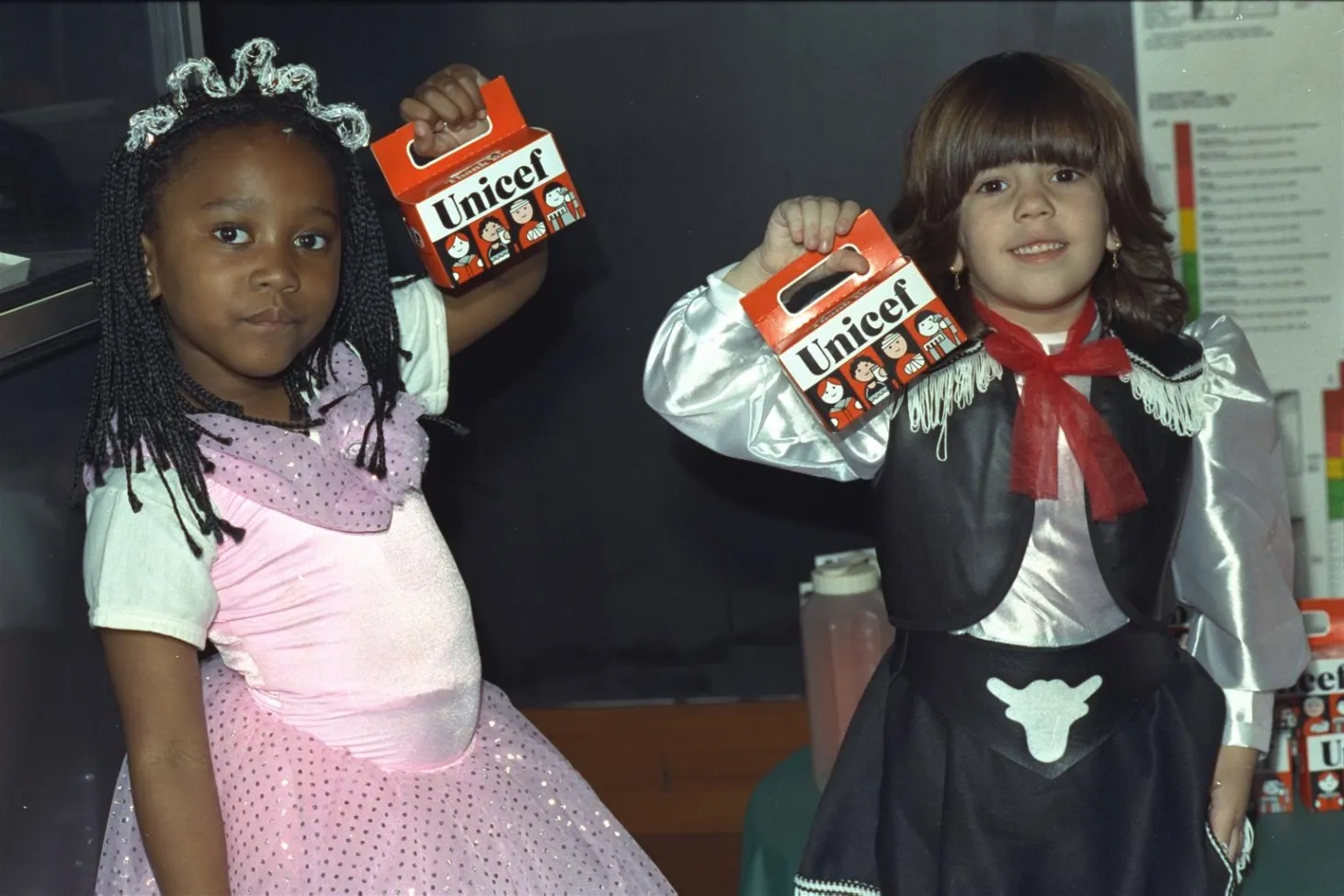 Deux filles déguisées portent des tirelires orange.