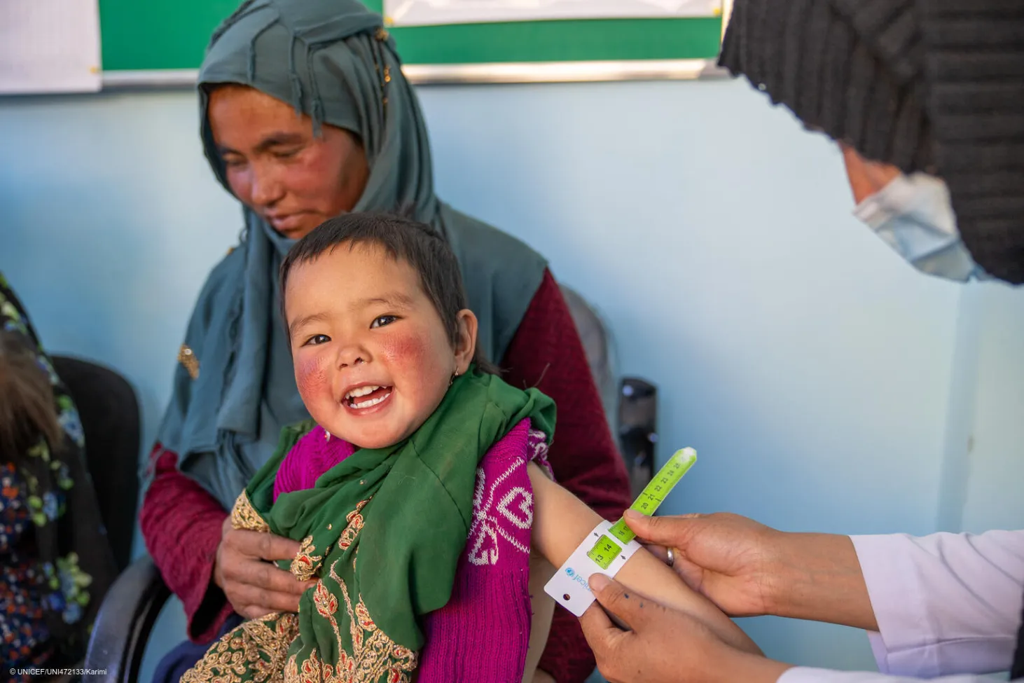 Un médecin mesure le bras d’un enfant à l’aide d’un bracelet millimétré. 