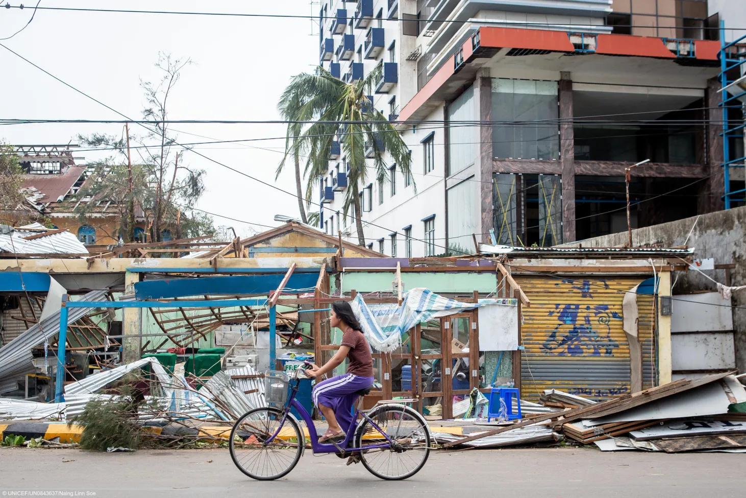 Une femme passe à vélo devant des immeubles endommagés par le passage du cyclone Mocha dans l’État de Rakhine, au Myanmar, le 14 mai 2023. 