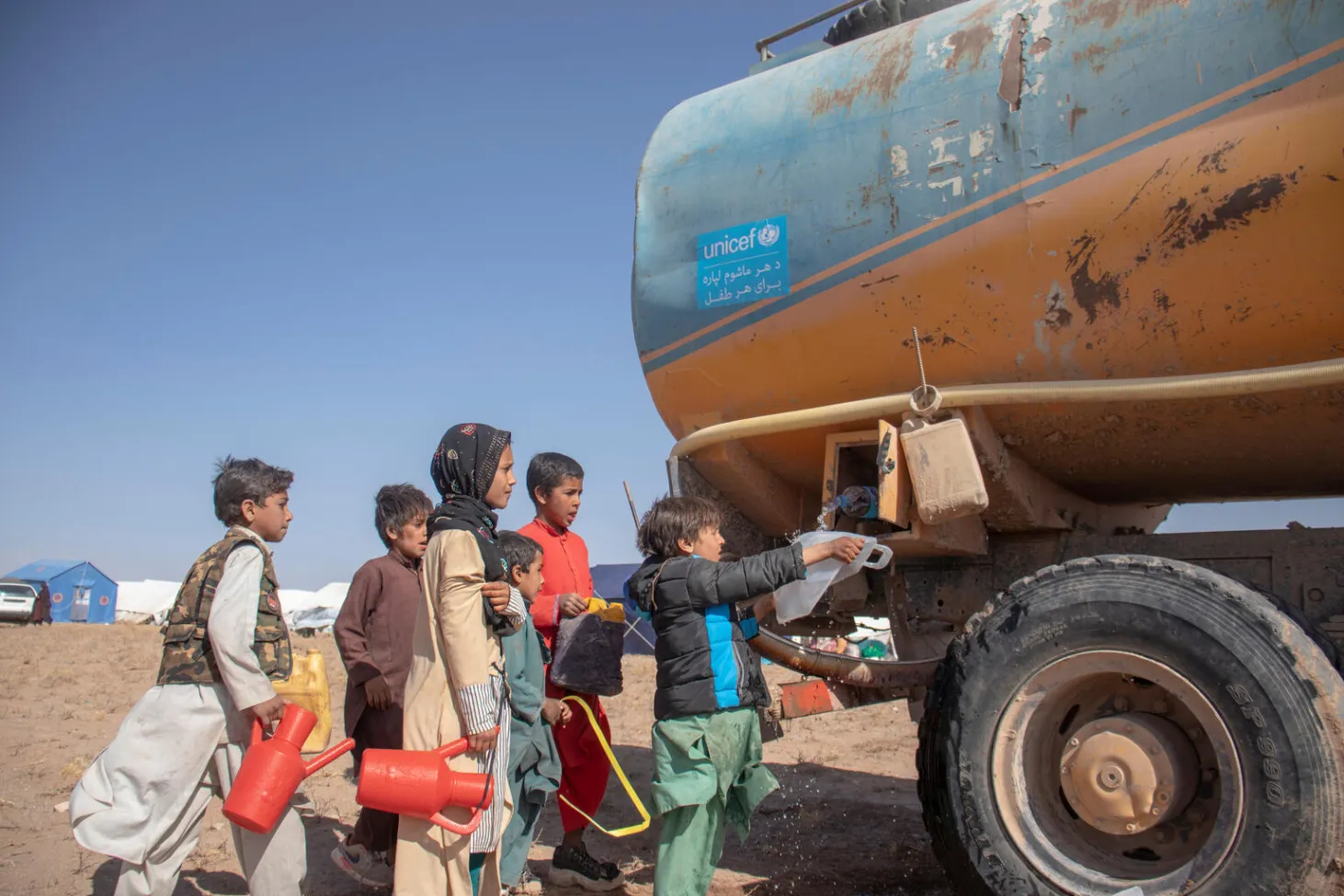 A group of children collect water from a UNICEF water truck in Afghanistan.