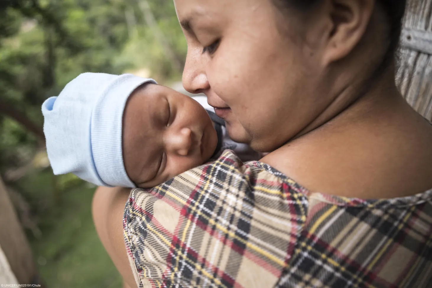 A mother holds her newborn baby close to her face. 