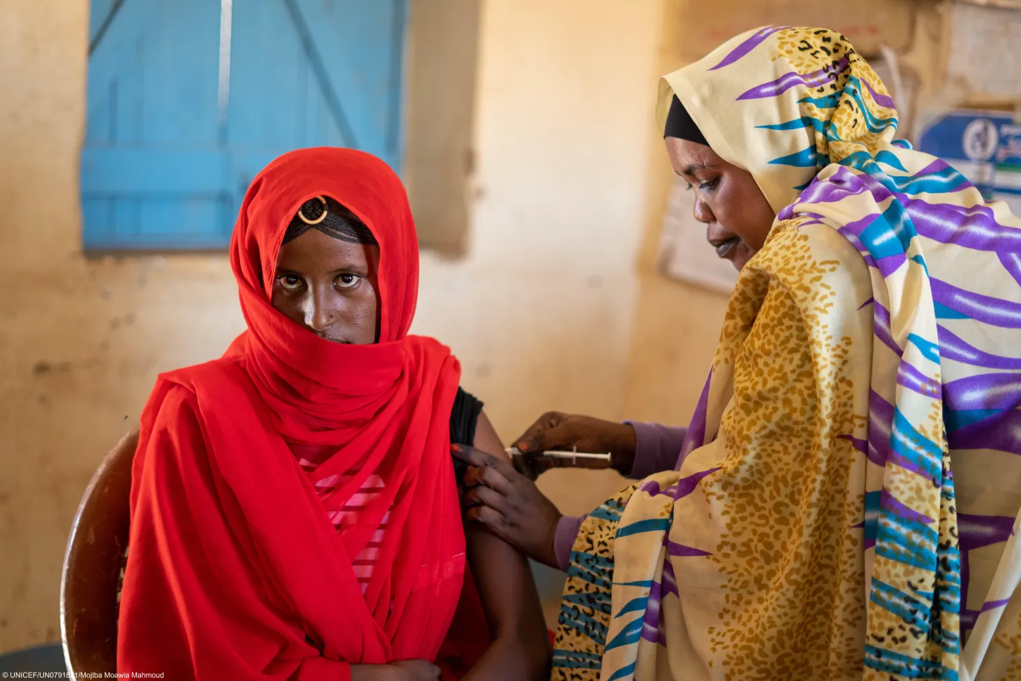 A vaccinator administers a vaccine on the arm of a woman. 