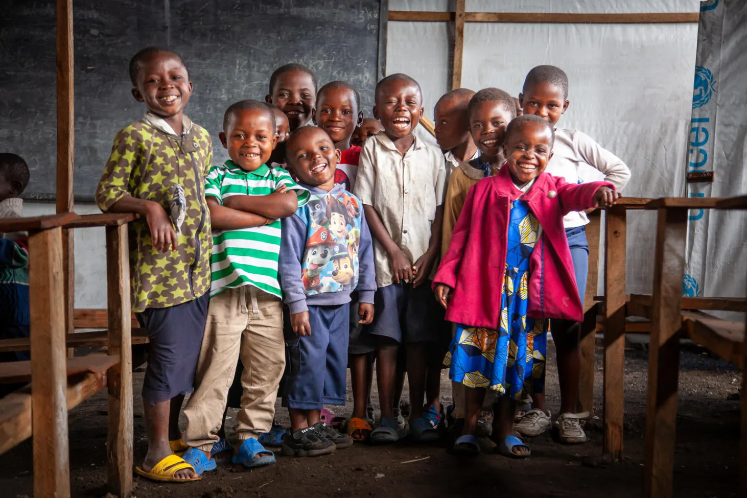 A group of children smile at the camera at a UNICEF-supported temporary learning space in The Democratic Republic of the Congo. 