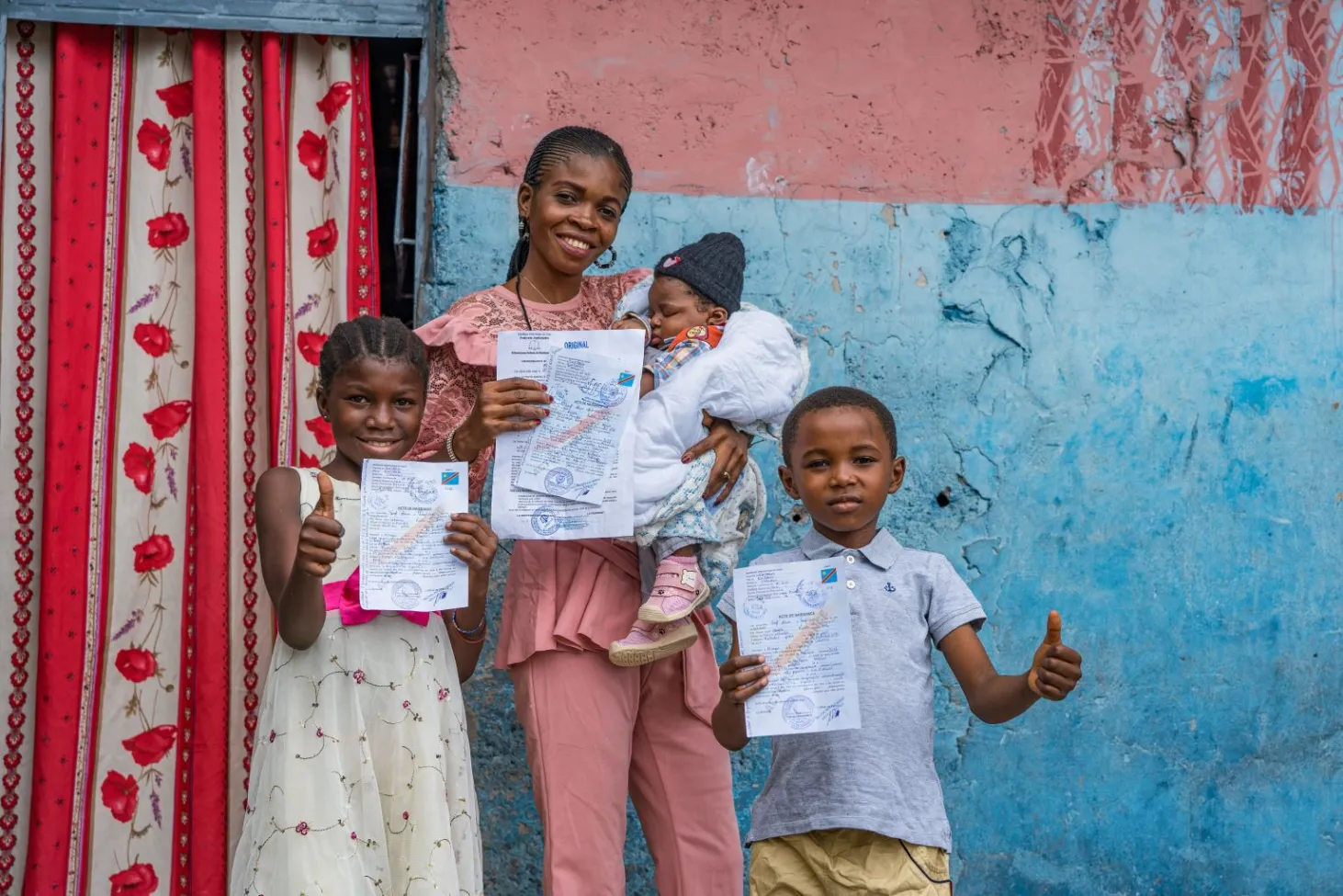 In Kinshasa, Democratic Republic of the Congo, Noella holds up her newborn’s birth certificate as her two other children hold up theirs. 