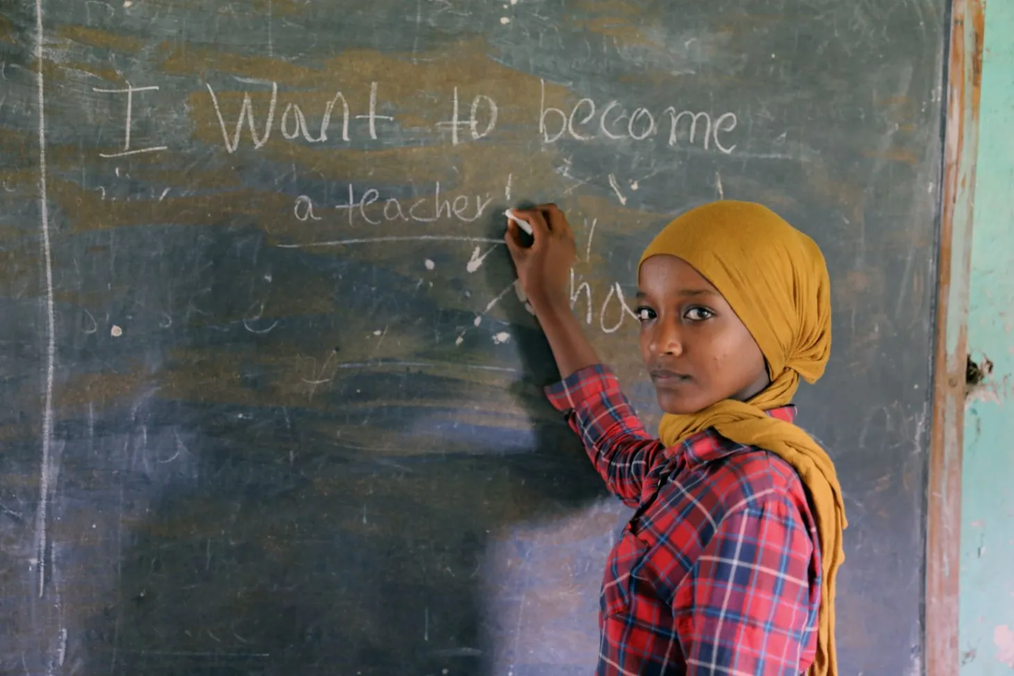 Dans une salle de classe en Éthiopie, la jeune Zemzem, âgée de 13 ans, regarde l’objectif alors qu’elle se tient devant un tableau sur lequel elle a écrit : « Je veux devenir enseignante ». 
