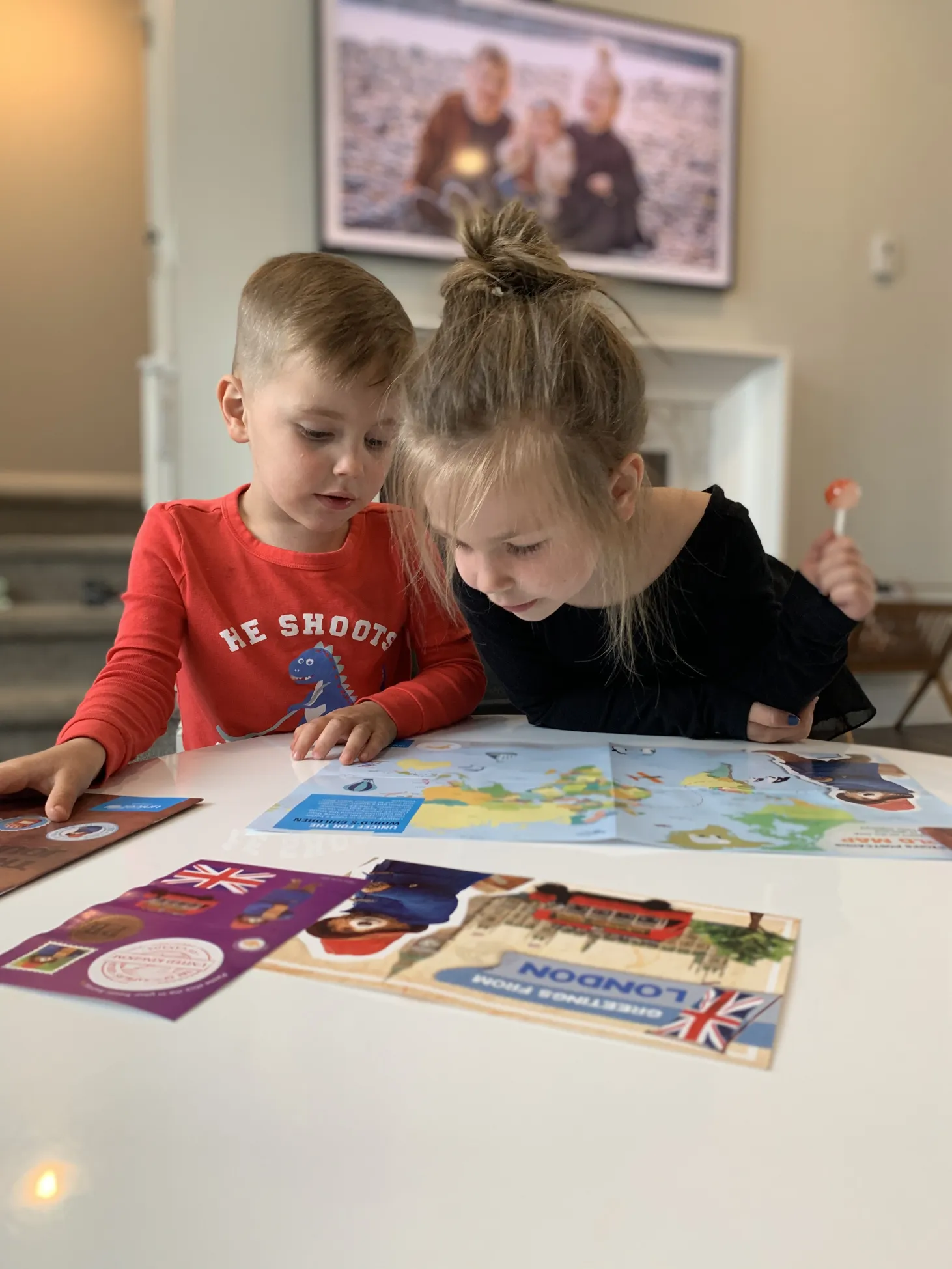 A boy and a girl interact with Paddington's Postcards package in their living room. 