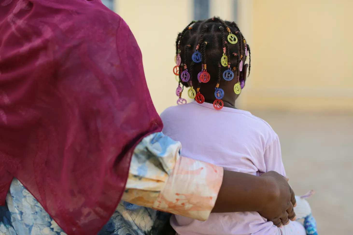 Assourita, a 5-year-old girl who was a victim of an explosive device, is with her mother who wraps her arm around her. 