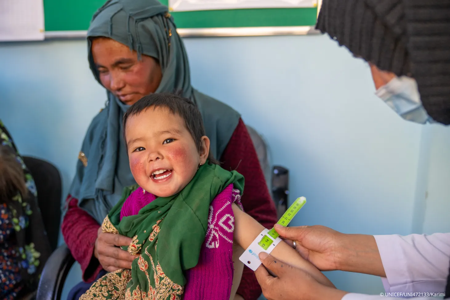 A girl smiles while getting the arm circumference measured for malnutrition. 