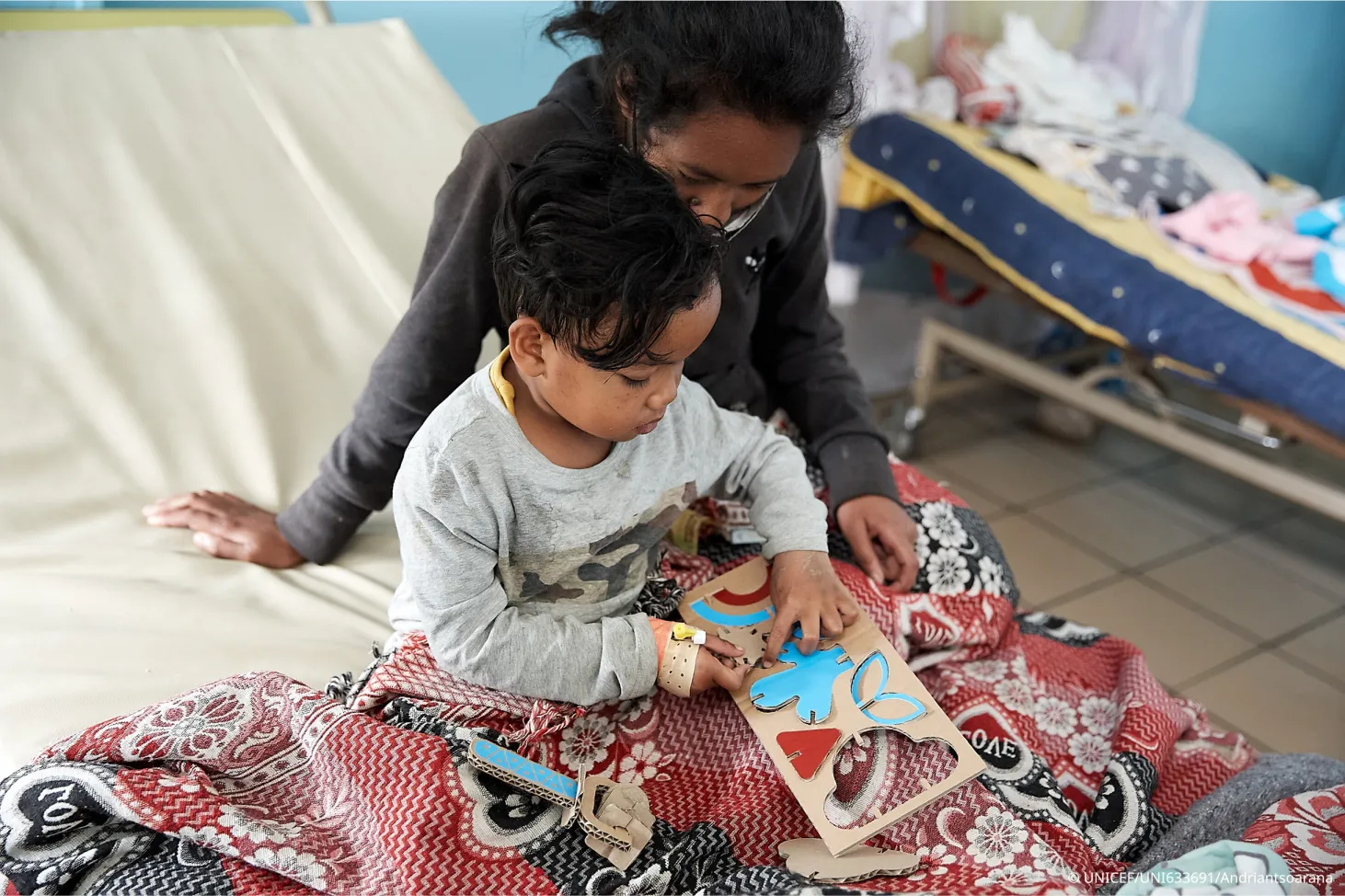  At a heath care center, a nurse and a child play with a cardboard puzzle