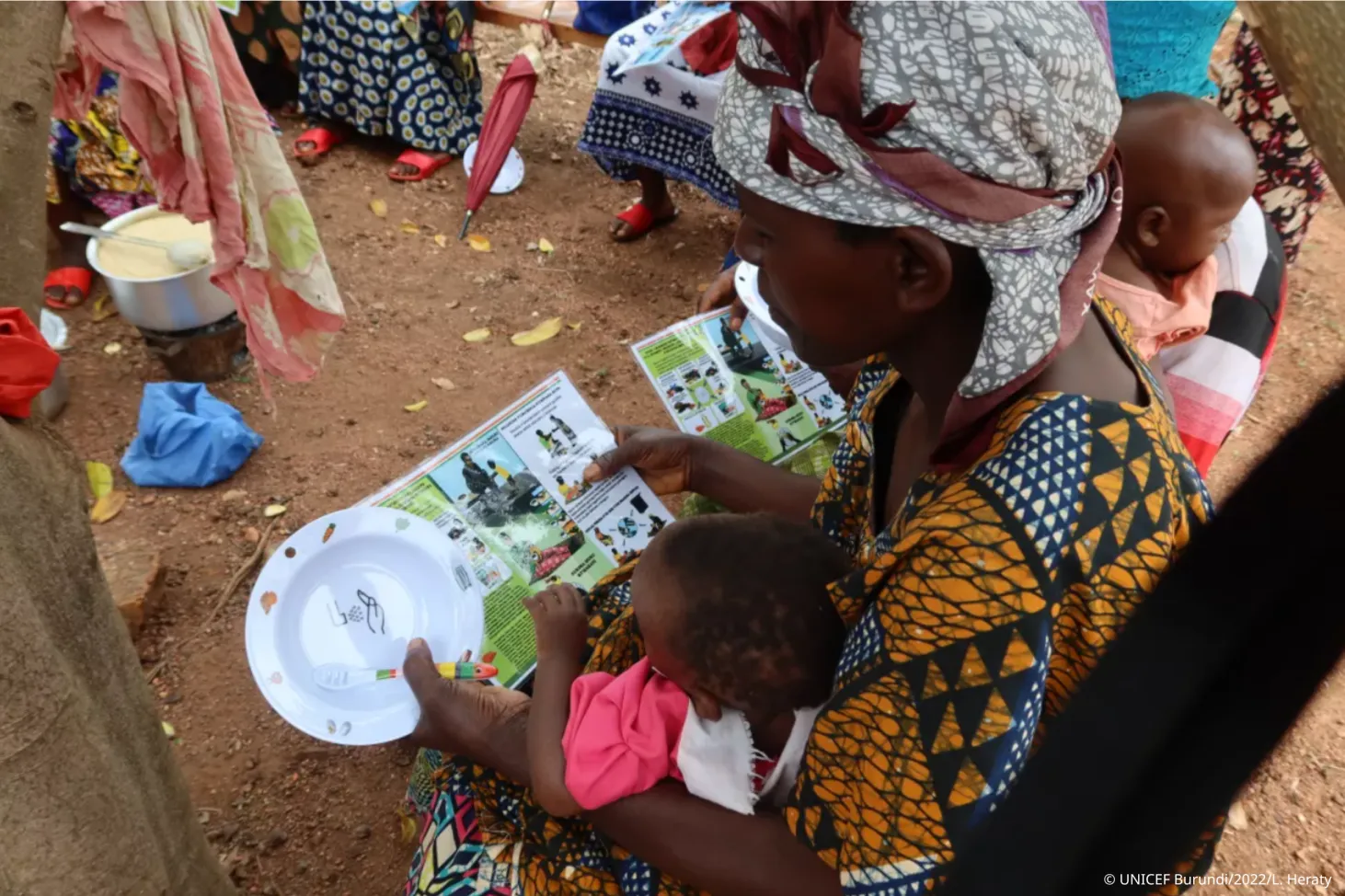 A volunteer is leading a mother-to-mother support group, she is holding a feeding bowl in her hand.