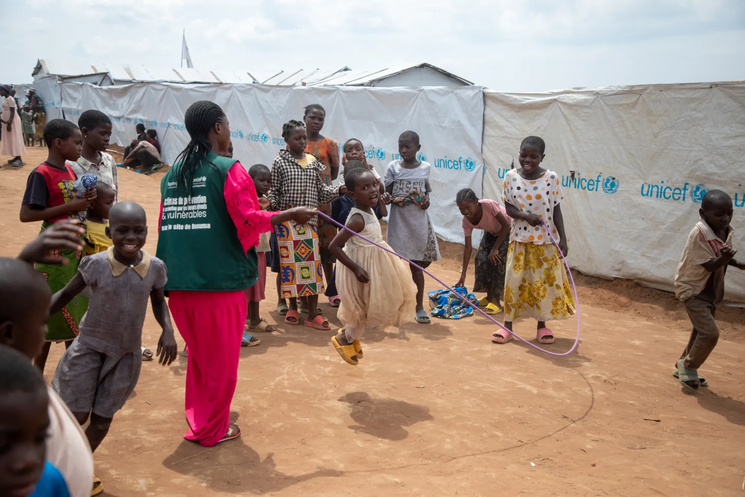Une fille saute à la corde avec un groupe d’enfants.