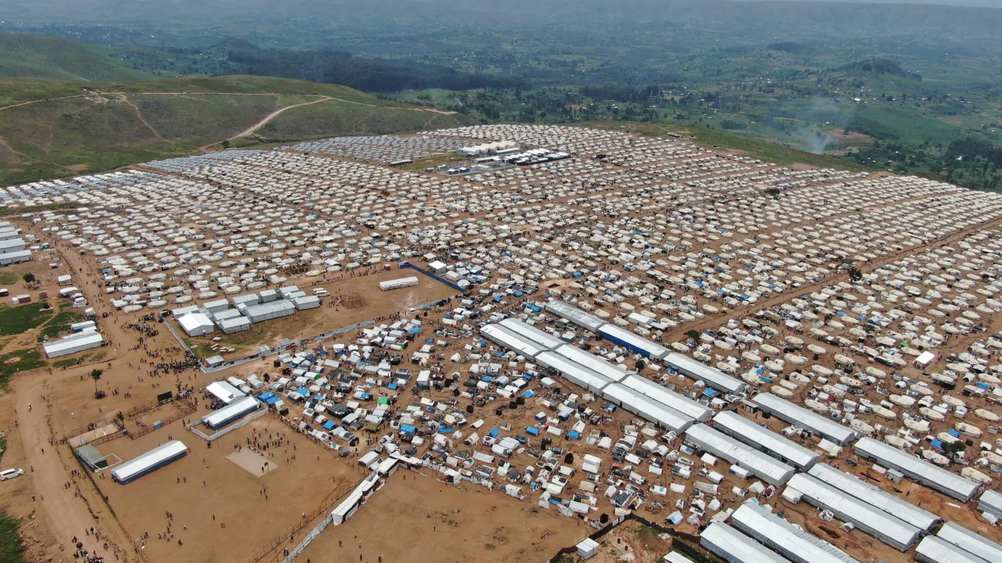 Vue aérienne d’un vaste campement densément peuplé, composé de milliers de petites tentes et d’abris temporaires.