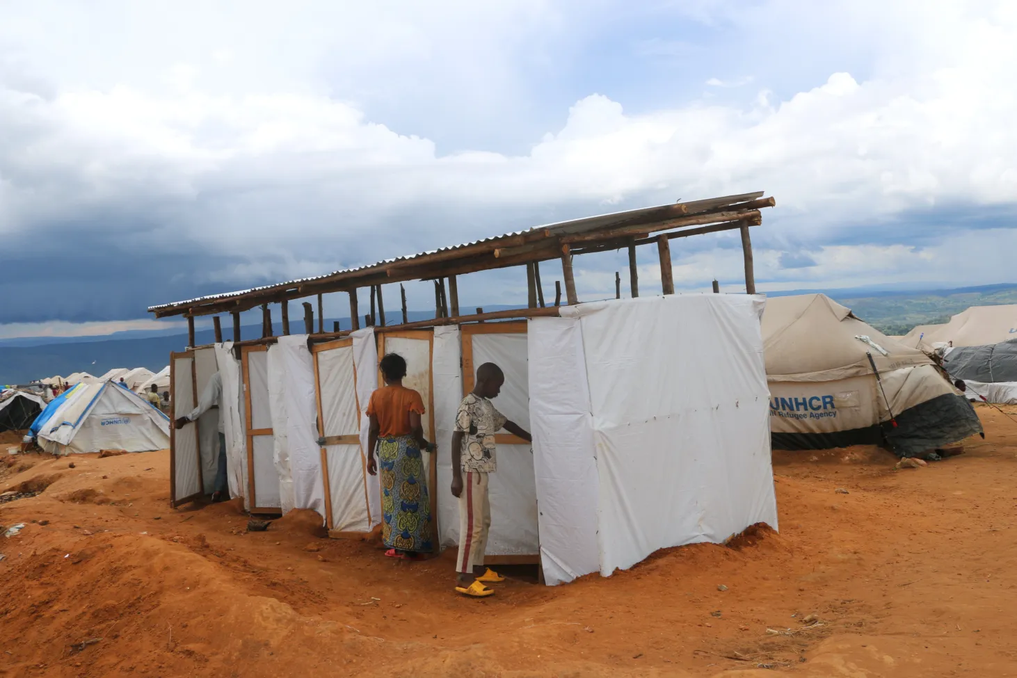 Bloc de latrines temporaires faites de cadres en bois et de draps blancs.
