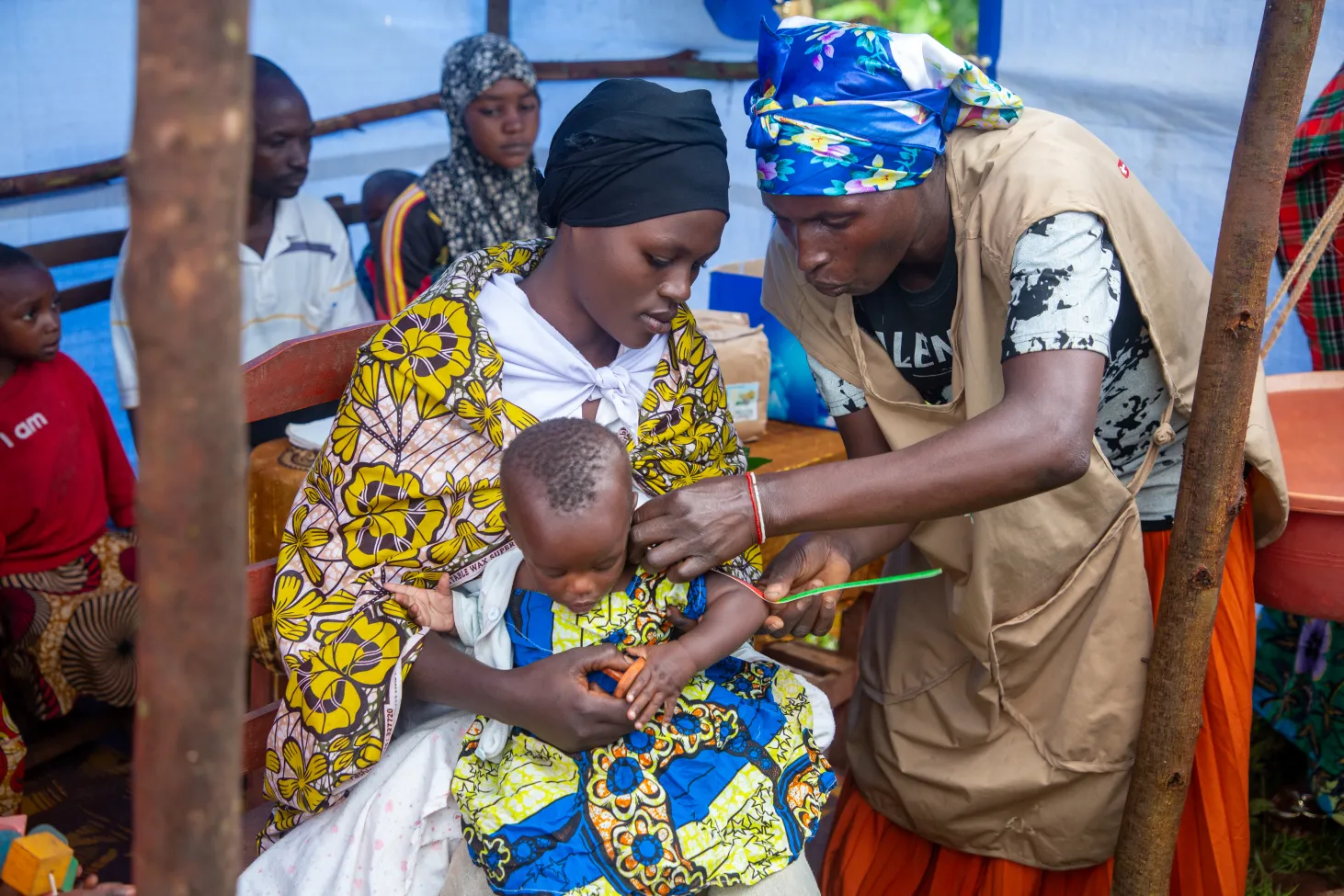 Une travailleuse de la santé communautaire mesure la circonférence brachiale d’un enfant à l’aide d’un ruban millimétré pour dépister la malnutrition.