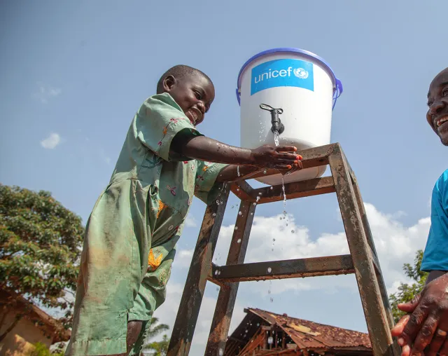 La responsable du programme WASH de l’UNICEF discute avec une jeune fille alors qu’elle se lave les mains afin d’empêcher la propagation du virus Ebola, près de Mangina, au Nord-Kivu, en République démocratique du Congo (RDC).