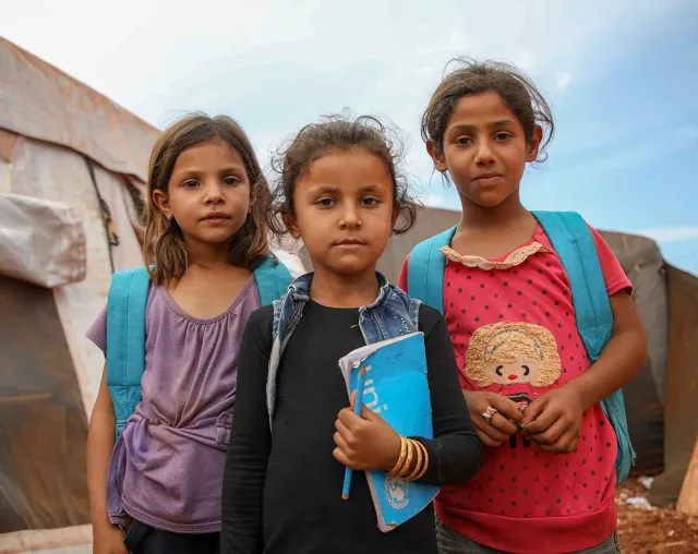 Des enfants se tiennent devant des tentes servant de salles de classe soutenues par l’UNICEF, dans la ville d’Idlib, dans le nord de la Syrie. Source: UN0248378.