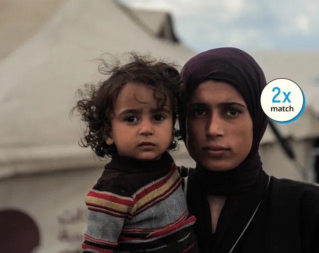 Woman holding a young child at a displacement camp in Gaza.